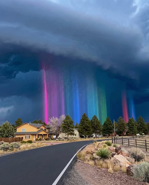 astrooalert's tweet photo. RAINBOW RAIN CURTAINS UNDER A STORM

The street was dark and silent… then the rain started glowing in colors.

This happened in the Southwest high desert (Arizona/Northern New Mexico style) when a thick storm base moved in and the Sun was still low enough to hit the rain from the side.

Those vertical “color pillars” are a rain shaft lit at the perfect angle — sunlight enters the falling droplets and splits into a spectrum, but because the rain is dropping in narrow curtains, the colors show up as straight bands instead of one wide arc.

The sparkly look comes from heavy drops catching light as they fall, like tiny reflections flashing through the curtain.