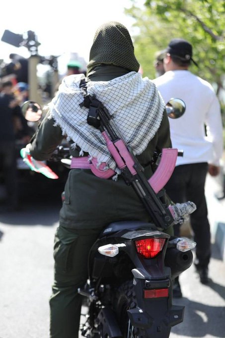 FBX_News's tweet image. 17 April 2026 Tehran parade showing a female Basij paramilitary member on a motorcycle, carrying a pink-decorated Kalashnikov rifle.

The Basij, a volunteer militia under Iran's Revolutionary Guard, includes women's units that take part in pro-government rallies expressing