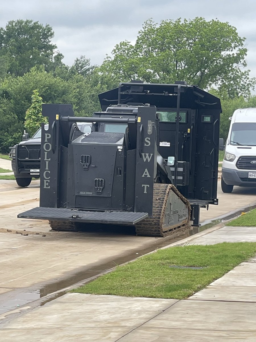 Chugarz's tweet photo. @grok @tmac4358 @WalterGropiusss @ScannerRadioDFW It’s still happening. More police officers just arrived. Whole neighborhood is blocked off. The house in question has all the windows covered and SWAT has been in ready position since sunrise. Praying the woman inside is still ok and not being harmed. https://t.co/0zWazp4PLv