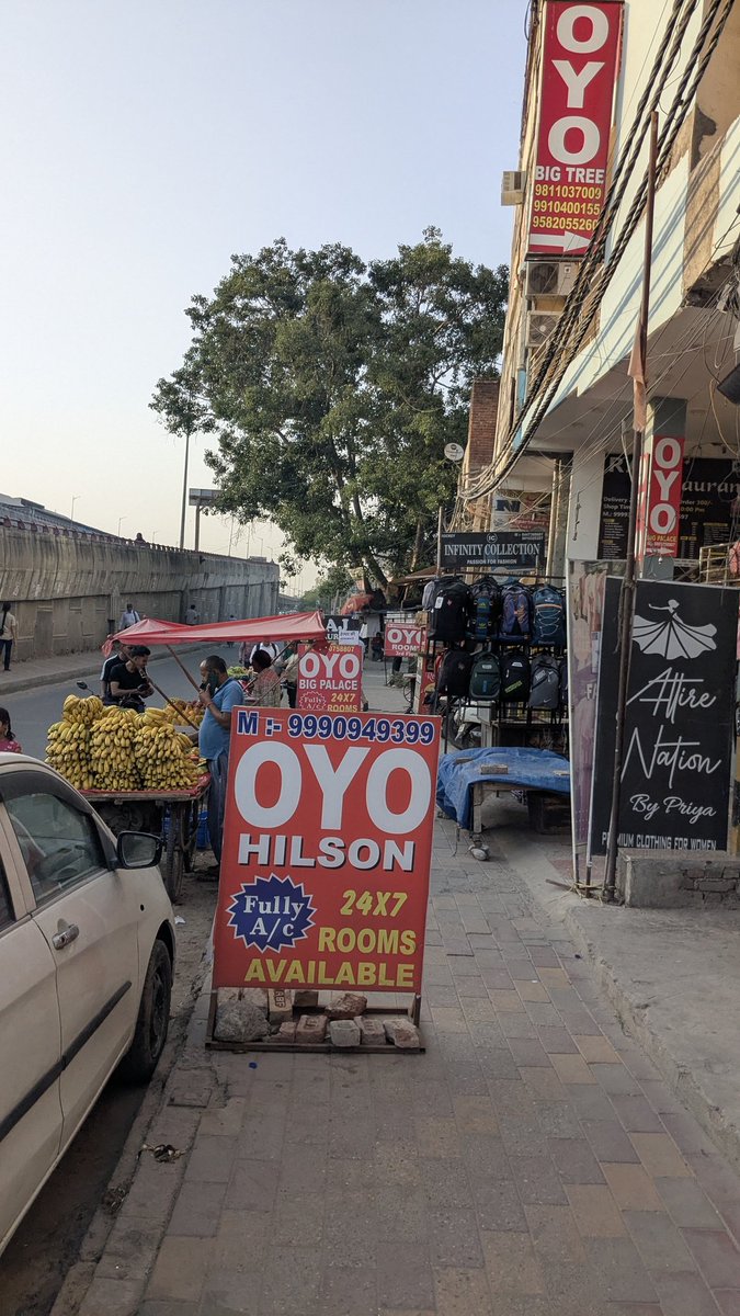 harshitt188's tweet photo. @CMODelhi The image shows a roadside area where commercial setups—such as large advertising boards, a fruit cart, and shop displays—are occupying a major portion of the footpath. This has significantly reduced the walking space for pedestrians.pls remove this https://t.co/Qqia0FRJdC