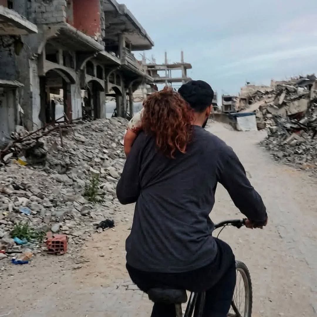 dn_osama_rabee's tweet photo. A father rides his bicycle while holding his injured daughter, her hair stained with blood in his trembling hands… a scene that captures the depth of pain in Gaza. https://t.co/deN7F3NuTs
