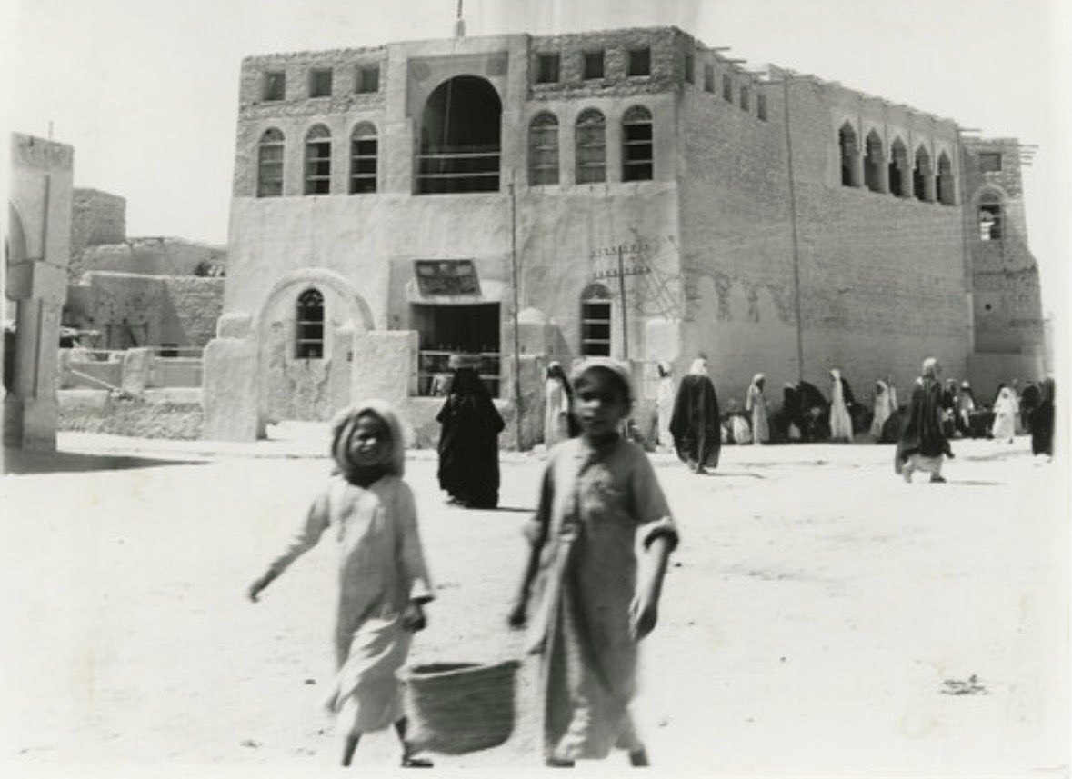 ArabiaEastern's tweet photo. Two boys carry a basket past the barracks which sit next to the Souq Al-Khamis, Al-Hofuf (1946-1954) https://t.co/C9fOaeHTcE