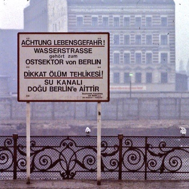 diaspora_turk's tweet photo. 51 yıl önce, 11 Mayıs 1975 günü, bir Anneler Günü’ne denk geliyordu.

Ramiz ve Münevver Mert çifti, Kreuzberg’in doğusundaki eski apartmanlardan birinde oturuyordu. O gün hem Çetin’in doğum günü hem de Anneler Günü’ydü. 5 yaşındaki çocukları Çetin, yeni ayakkabılarıyla sokakta top oynuyordu. Birazdan ailece pikniğe gideceklerdi.

Spree Nehri’nin hemen kıyısındaki Gröbenufer üzerinde oyuna dalan Çetin, nehre doğru giden topun peşinden koştu. Ardından bir anda gözden kayboldu. Çocuğun nehre düştüğünü çevrede birçok kişi gördü. Diğer çocuklar yardım için bağırıp çağırdı ama onu kurtarmak için nehre giren olmadı. Nehrin bir tarafı Doğu, diğer tarafı Batı Almanya’ya aitti. Sınır ihlali yapmak yasaktı. Askerler Çetin’in çırpınışını gördü ama nehre girmeye cesaret edemedi. Herkes “Kurallar”dan bahsediyordu. Karşı taraftan ateş açılabilirdi.

Çetin onca insanın gözü önünde çırpınarak boğuldu. Kendi doğum gününde ve bir Anneler Günü’nde, henüz 5 yaşındayken hayatını kaybetti. Dalgıçlar Çetin’i tam 2 saat 5 dakika sonra nehirden çıkardı. Çetin’in ölümünü açıklamak için sınırlardan, anlaşmalardan, kurallardan bahsettiler. “Doğu tarafına sürüklendiği için onların sorumluluğundaydı.” dedi Batı yakası yetkilileri. “Düştüğü yer batıydı” cevabı geldi karşı taraftan.

Ramiz ve Münevver Mert çifti için hiçbir anlamı olmayan bu sözler sıralanıp gitti. Çocuklarının cenazesini almak için doğuya geçtiler. Geçerken vize alıp, vize ücreti ödediler. Çetin’in ardından Kreuzberg’de bir öfke büyüdü. Türkler ve göçmenler sokağa indi. Yürüyüşler, gösteriler birkaç gün devam etti.

Sonunda iki tarafın yetkilileri bir komisyon kurdu ve kriz durumları için arama-kurtarma anlaşması yaptı. Nehrin kenarına korkuluklar, can simitleri koydular, çift dilli uyarı tabelaları diktiler. Çocuklar için önlemler alındı. Çetin Mert, Berlin Duvarı’nın çocuk kurbanı olarak kayıtlara geçti, ismi diğer Kreuzbergli çocuklara umut oldu.​​​​​​​​​​​​​​​​​​​​​​​​​​​​​​​​​​​​​​​​​​​​​​​​​​
#AnnelerGünü