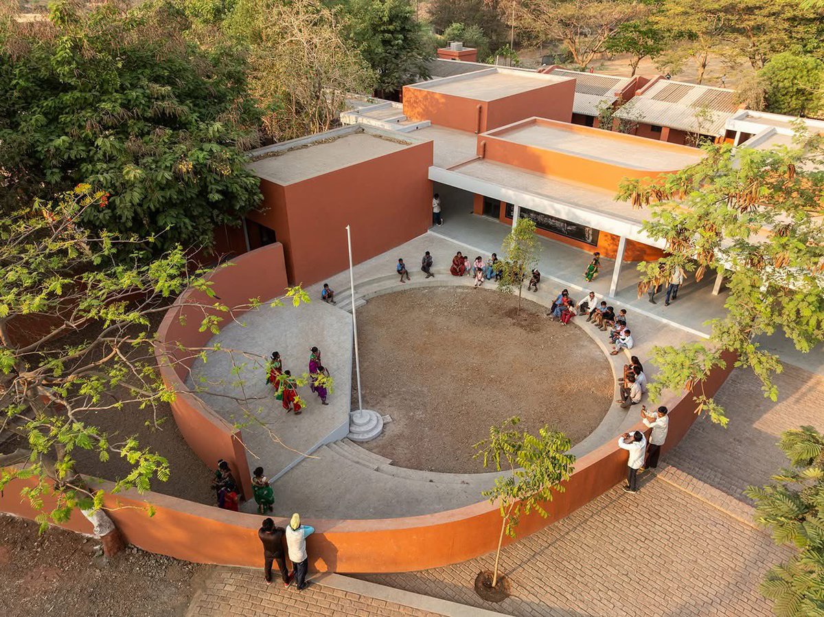 shavnyuyngah's tweet photo. A school is not a box children sit in. It is a space that teaches them before the lesson begins.

Belgaon Dhaga School. Nashik, Maharashtra, India. Architect: Pooja Khairnar, pk_iNCEPTiON. 1,050 m². Completed 2025.

The existing school was a rigid linear block, one long row of classrooms facing an open ground. The intervention refused to repeat that logic. Instead a series of smaller blocks arranged like a village, connected by courtyards, shaded corridors and brick terraces that blur the boundary between classroom and playground.
Buildings oriented to the sun path for maximum shade. Perforated openings and louvered panels for natural ventilation. Local brick throughout. No air conditioning in a school that needs none.

The circular courtyard at the centre is not a design gesture, it is an amphitheatre, a gathering space, a flag ceremony ground, a place where the community sits in the evening.

This is what it looks like when an architect asks what children need from a building rather than what a building requires of children.
