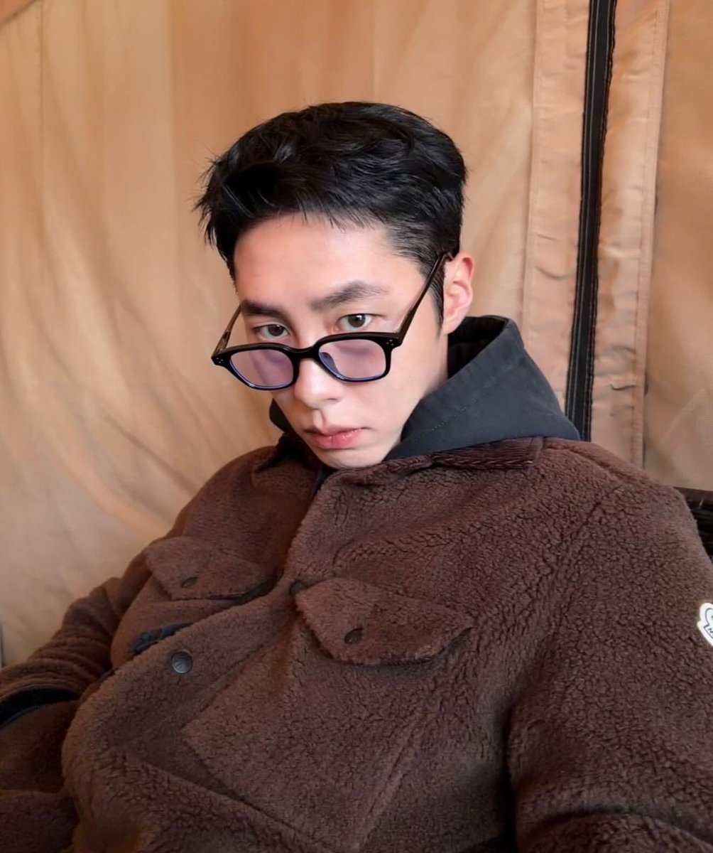 Jaewoock's tweet photo. The official I'm glamping, not camping, obviously stare. Do these glasses make me look like I’m judging your choice? Just pondering the absolute necessity of a leather-handled cooler while my Moncler jacket keeps me significantly cozier than anyone else here. https://t.co/jji3uwDhTr