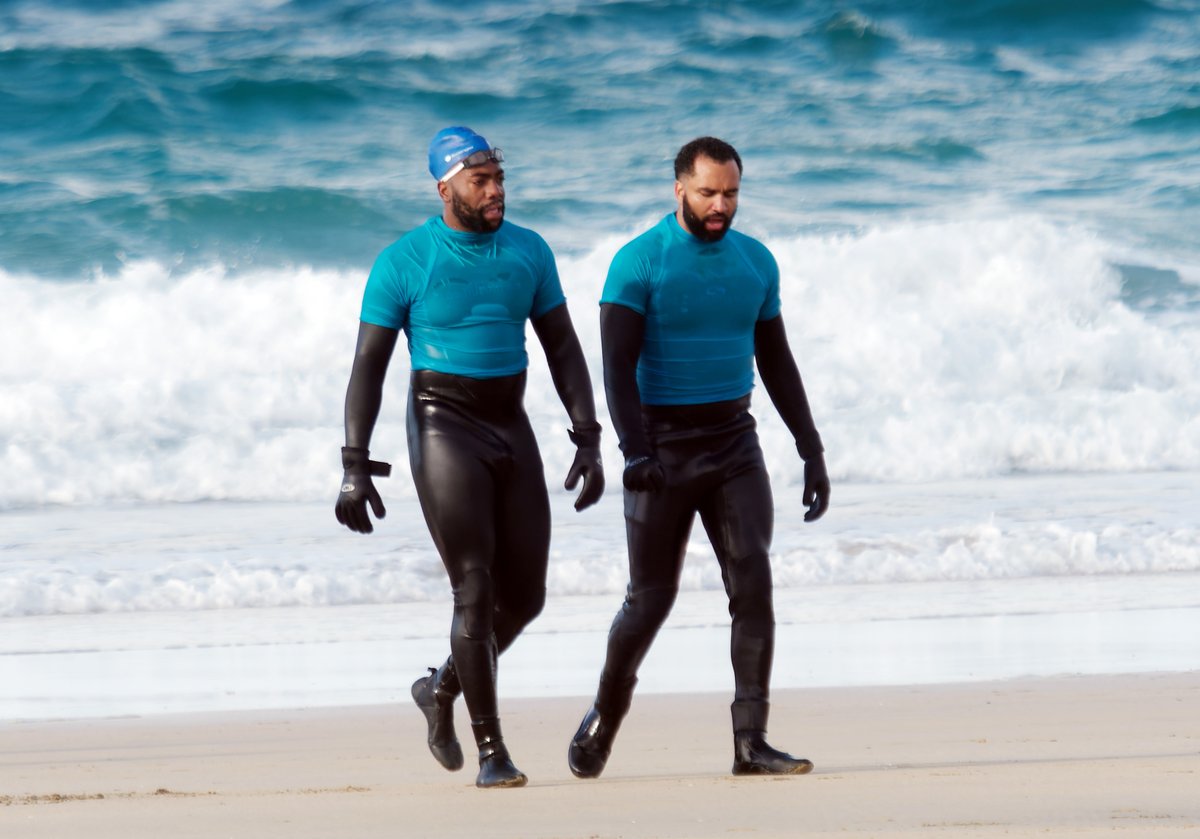 robertTmojo's tweet photo. Show bizz corner. Help required. Can any gimlet eyed sleb spotters identify the guy to the right of actor Fehinti Balogun?. This picture was taken during a break in filming of "Down Cemetery Road" for AppleTV. The location is Fistral Beach, Cornwall, UK https://t.co/u7atCFKwcO