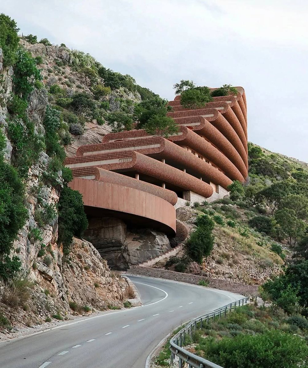 CapturedLtd's tweet photo. The Northern Apartments by Studio Precht and 10 Architects are a breathtaking example of topography-driven design. Located on the rugged coast of Albania, the building features terraced, curved slabs that mimic the natural flow of the hillside.  Stepping with the slope. https://t.co/aHlRd0PKXC