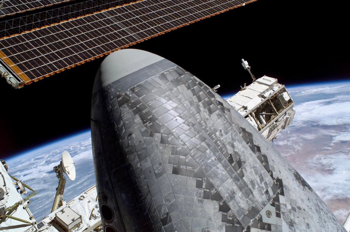 Boneyardsafari's tweet image. A look at Orbiter Discovery OV-103’s underside nosecone thermal protection tiles during STS-114.  Part of the P1 truss and a solar array are visible in the background of the International Space Station.  Newer thermal tiles are black and older ones are gray. #spaceshuttle #nasa