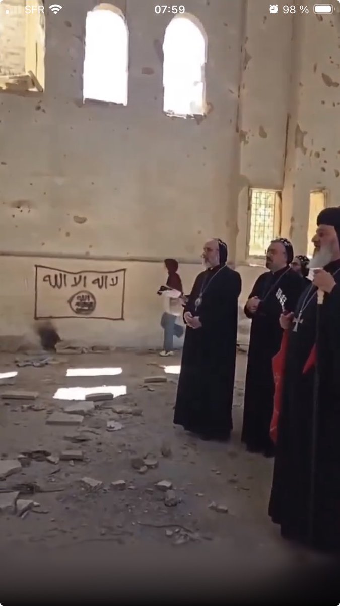 deSyracuse's tweet photo. #Syria - Incredible scene in #Deirezzor where orthodox priests are praying in a devastated church where Islamic state flag is still painted on the wall https://t.co/fz5YDEEdIi