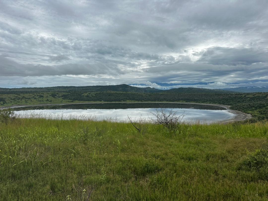Be like water - not luxurious but essential and valuable for life, does'nt seek attention yet it sustains everything. #omangwasafarisandmothernature.Still waters in the crater, wild skies above. 
#lakeNyamunuka
#queenelizabethnationalpark
#breathtakingviews
#greenery
#wildwonders