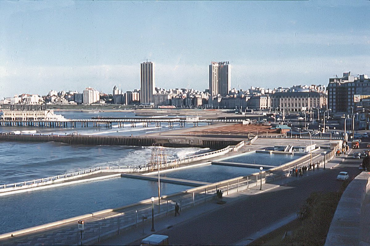Mar del Plata a fines de la década del '60. Piletas Punta Iglesia,  Edificio Palacio Cosmos (Pepsi), el Demetrio Elíades  (Havanna) en el tramo final de su construcción y el cartel de Gancia en el muelle del Club de Pesca. Foto: Juan Enrique Gilardi