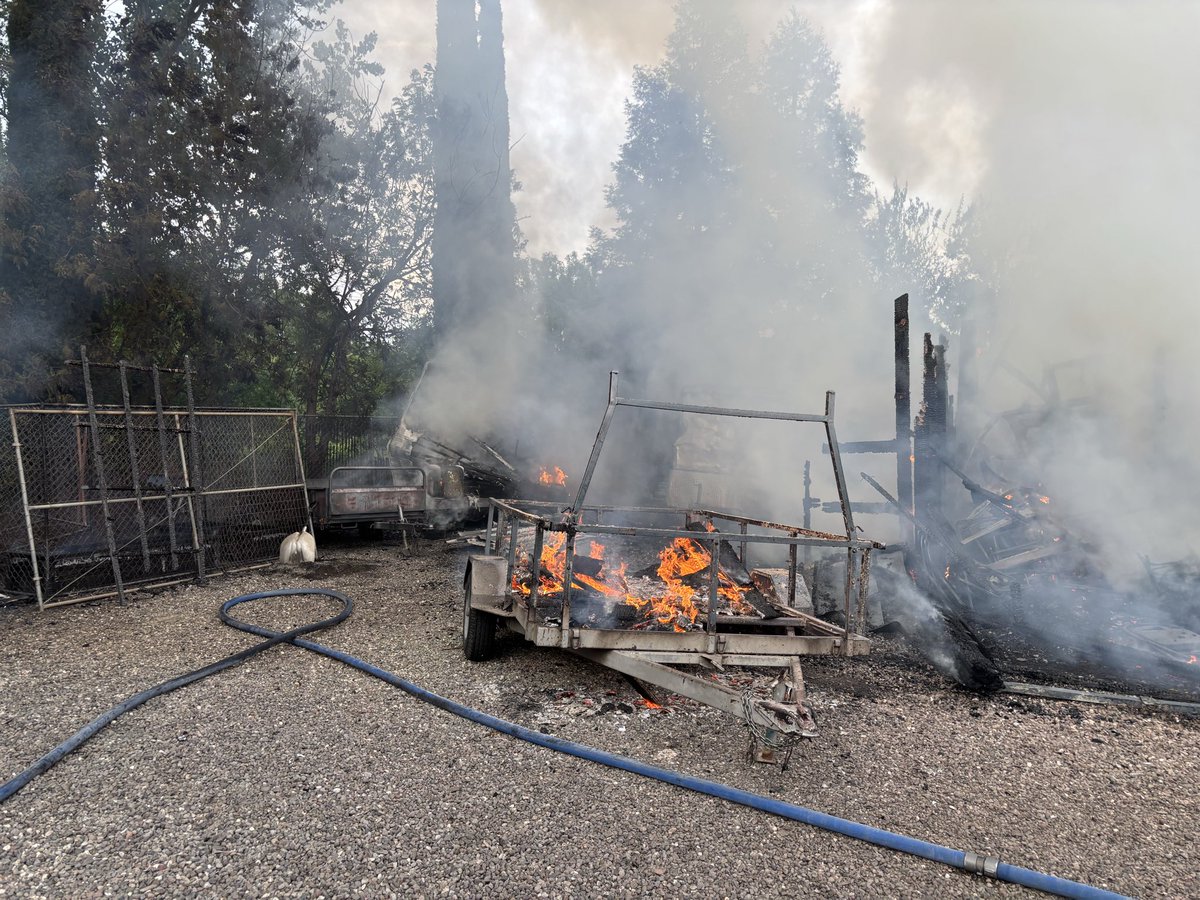 Firefighters at scene of a barn fire with extension to an unoccupied RV ...