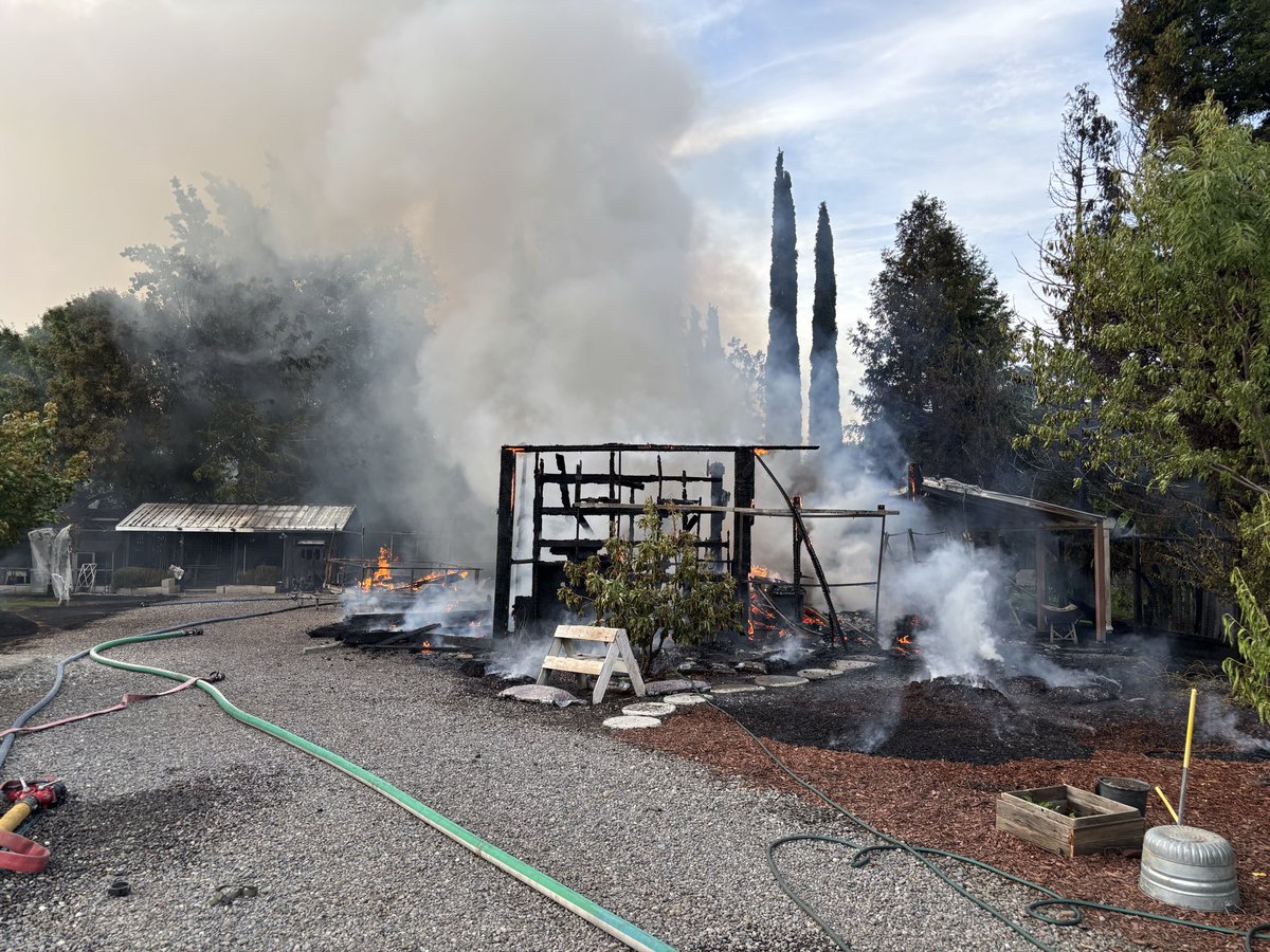 Firefighters at scene of a barn fire with extension to an unoccupied RV ...