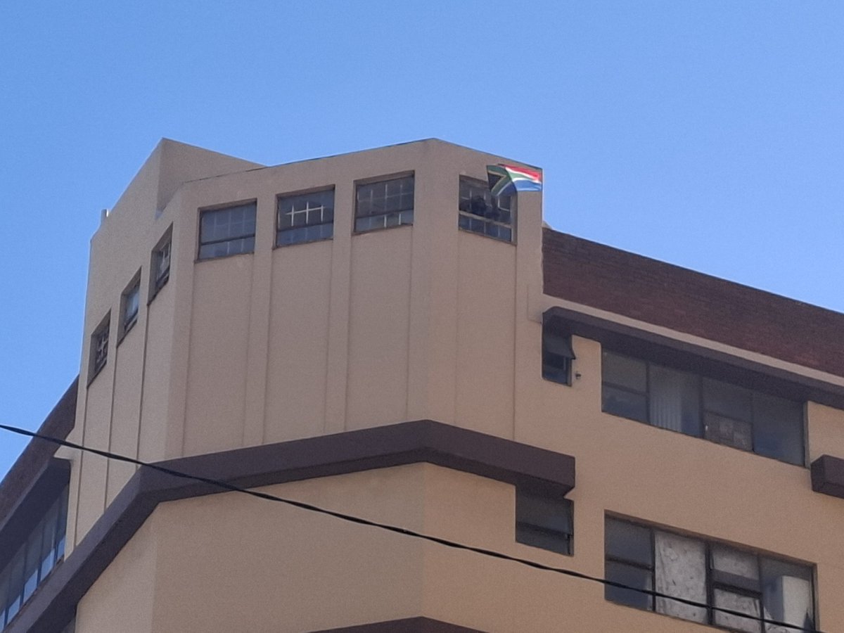 ZANewsFlash's tweet photo. PICS: Ngizwe Mchunu waves the South African flag on top of a block of flat that is being raided for drugs in the notorious Point area in Durban - KZN Tonight Podcast https://t.co/PWP0hP2os4