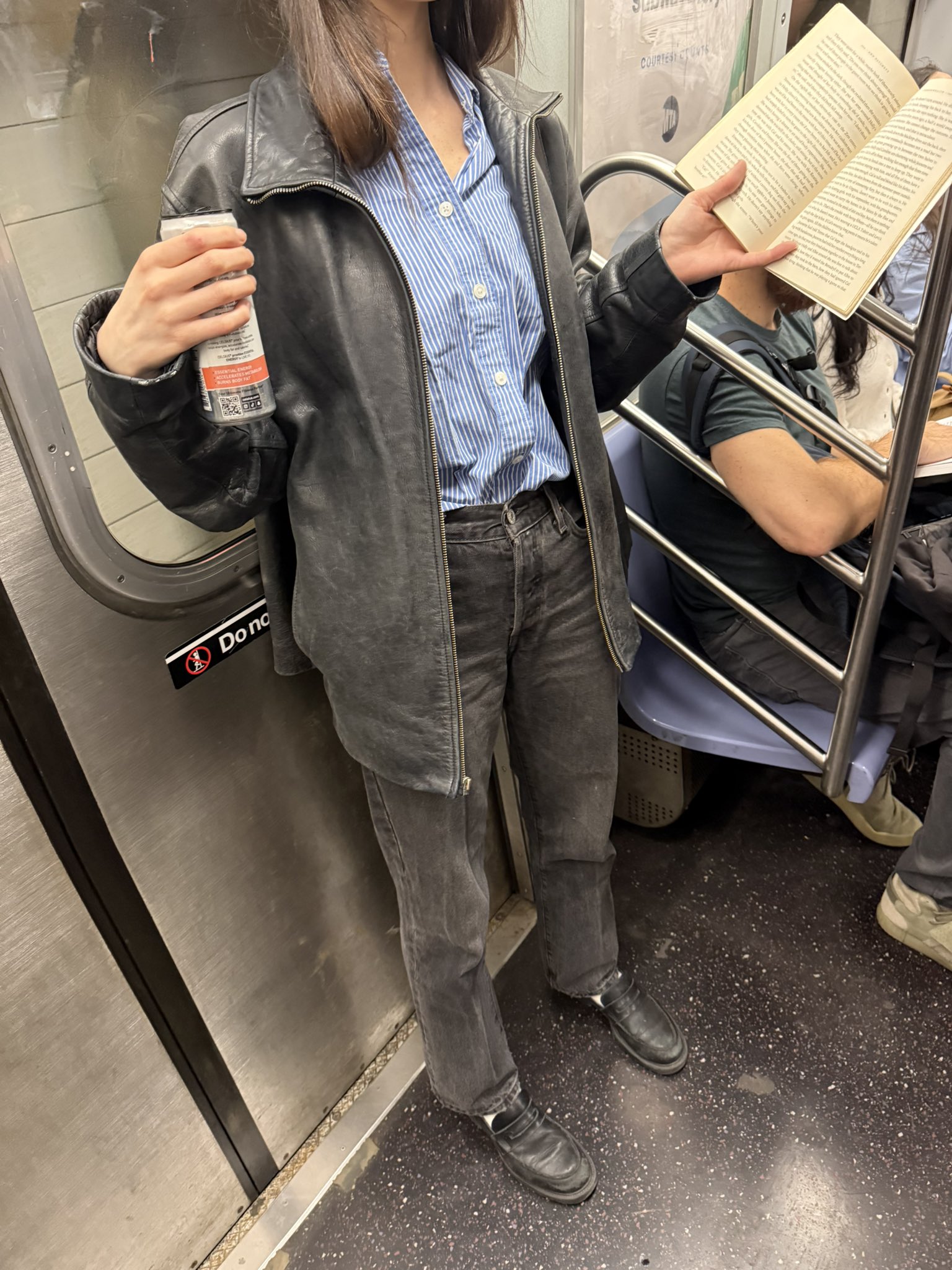 A worn leather jacket, dark denim, and loafers on the subway, posted on X by @rachcorrine