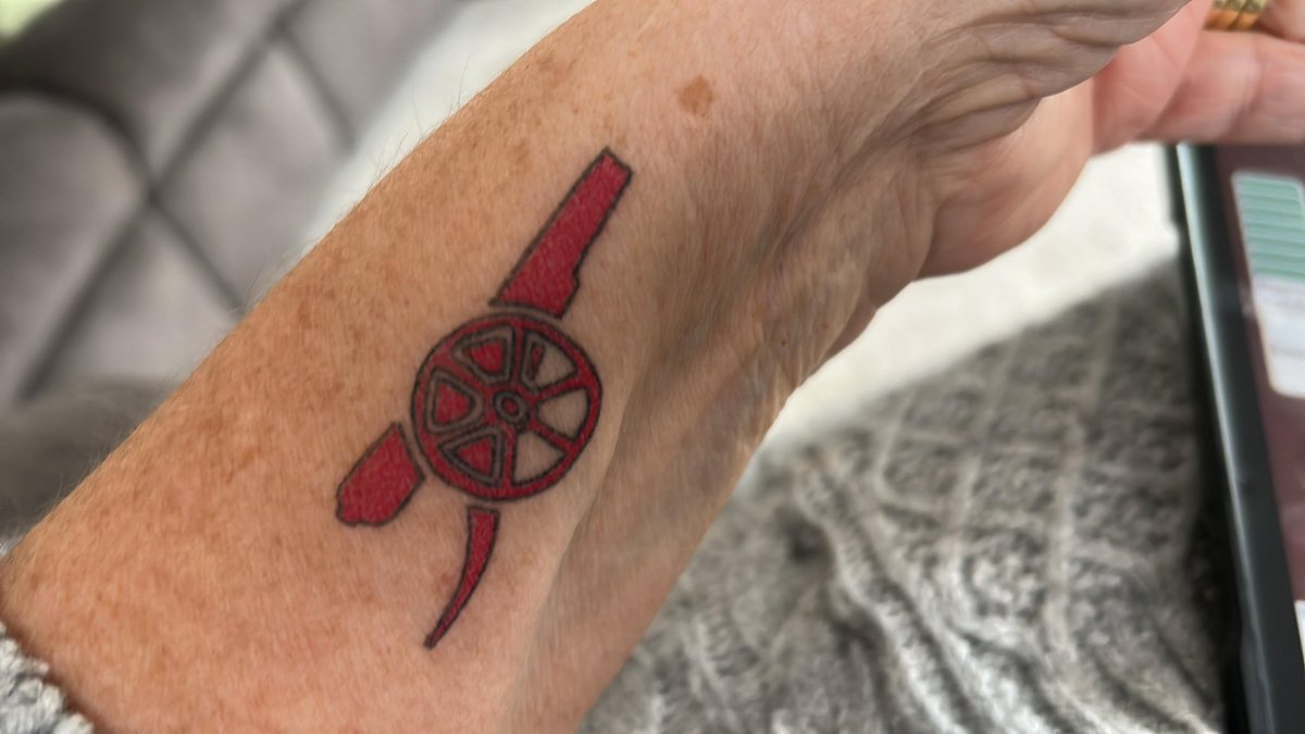 Webbster77's tweet photo. @Arsenal My mum has been a lifelong fan, and, on holiday last week, at the age of 77 she showed her dedication with these tattoos!  Any chance you could hook her up with a Cup final ticket PLEASSSE! We’ll obviously pay, just need a ticket and the red membership is closed! https://t.co/DvtKZR9lIl
