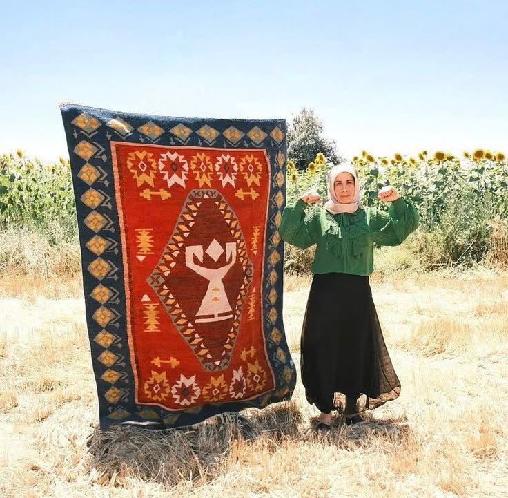 Dokuduğu kilimin önünde poz veren bir Türk kadını.