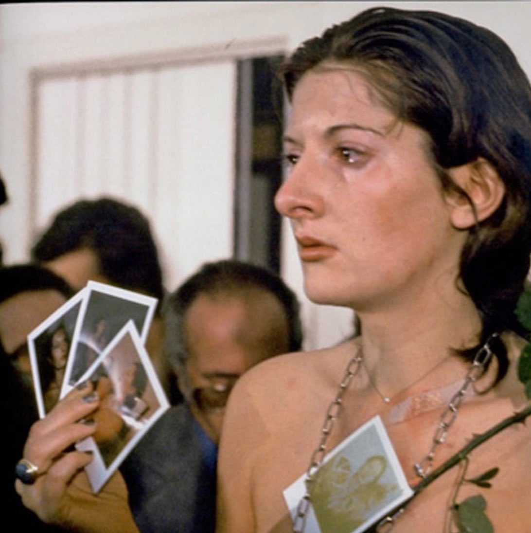 In 1974, Marina Abramović stood still for six hours and let strangers do anything they wanted to her.

The performance was called Rhythm 0.

Beside her was a table with 72 objects.

Some were harmless: a rose, feathers, honey, bread, wine, and perfume.

Others were weapons: