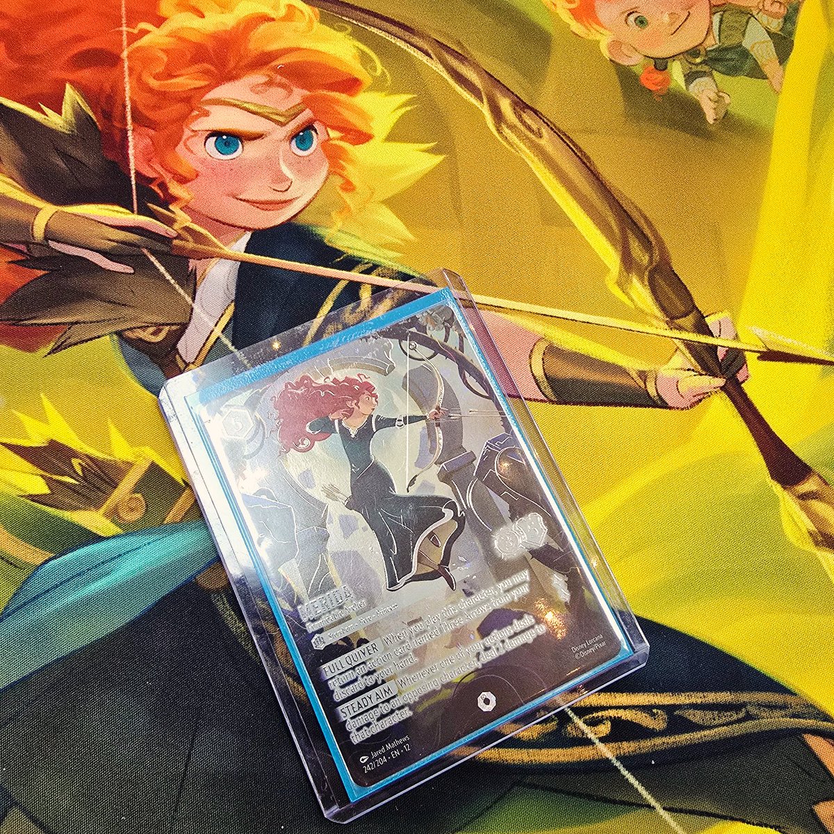 Illuminotts's tweet photo. While attending the @thedicecup @DisneyLorcana Set 12 pre-release event, part of the illuminotts community, Corey and Georgie, pulled THE ICONIC MERIDA - FORMIDABLE ARCHER!!! 🏹 
Congratulations to them ✨️
The card is beautiful and it is amazing to see an Iconic in person!! 🧡 https://t.co/b1vQVIL7Ex