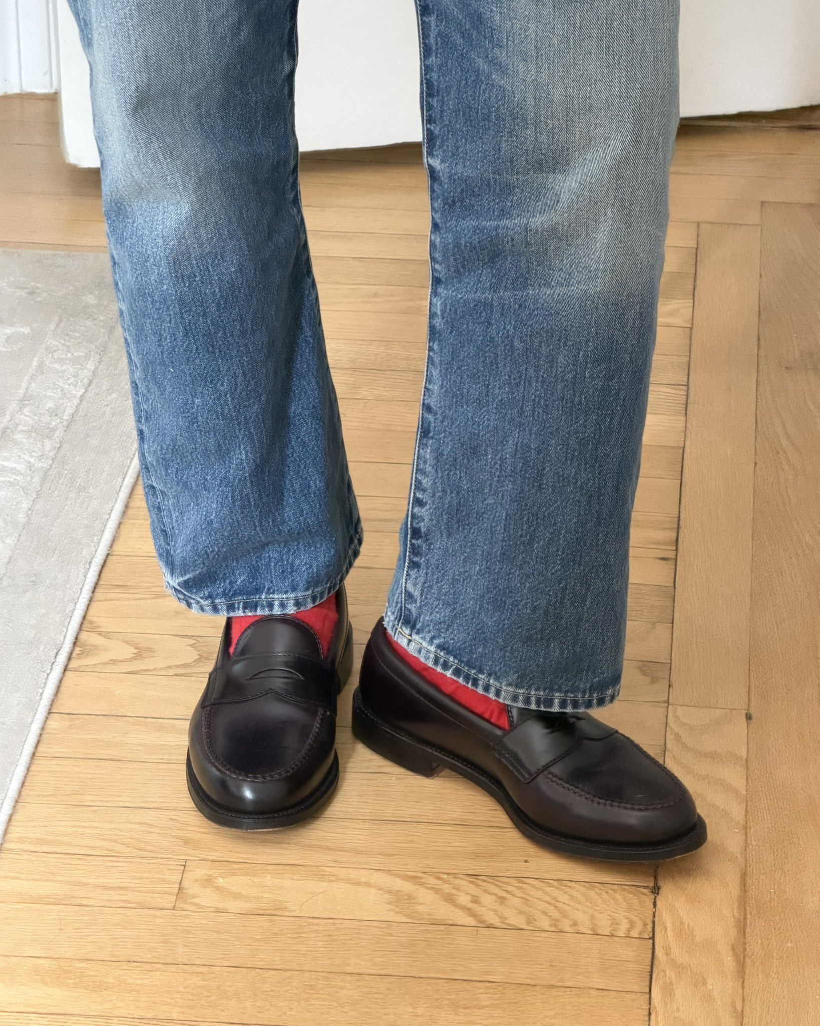 Dark jeans, brown loafers, and a cranberry crew sock showing at the hem, posted on X by @jakewoolf