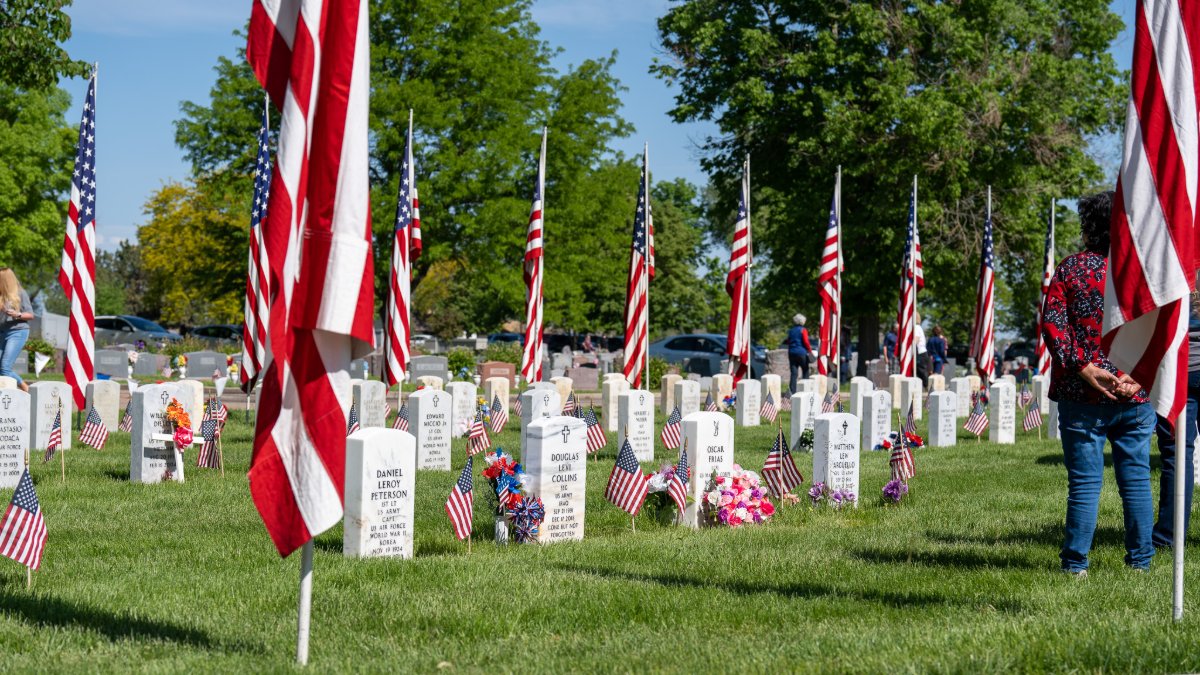 Solder gravestones adorned with American flags for a Memorial Day ceremony.