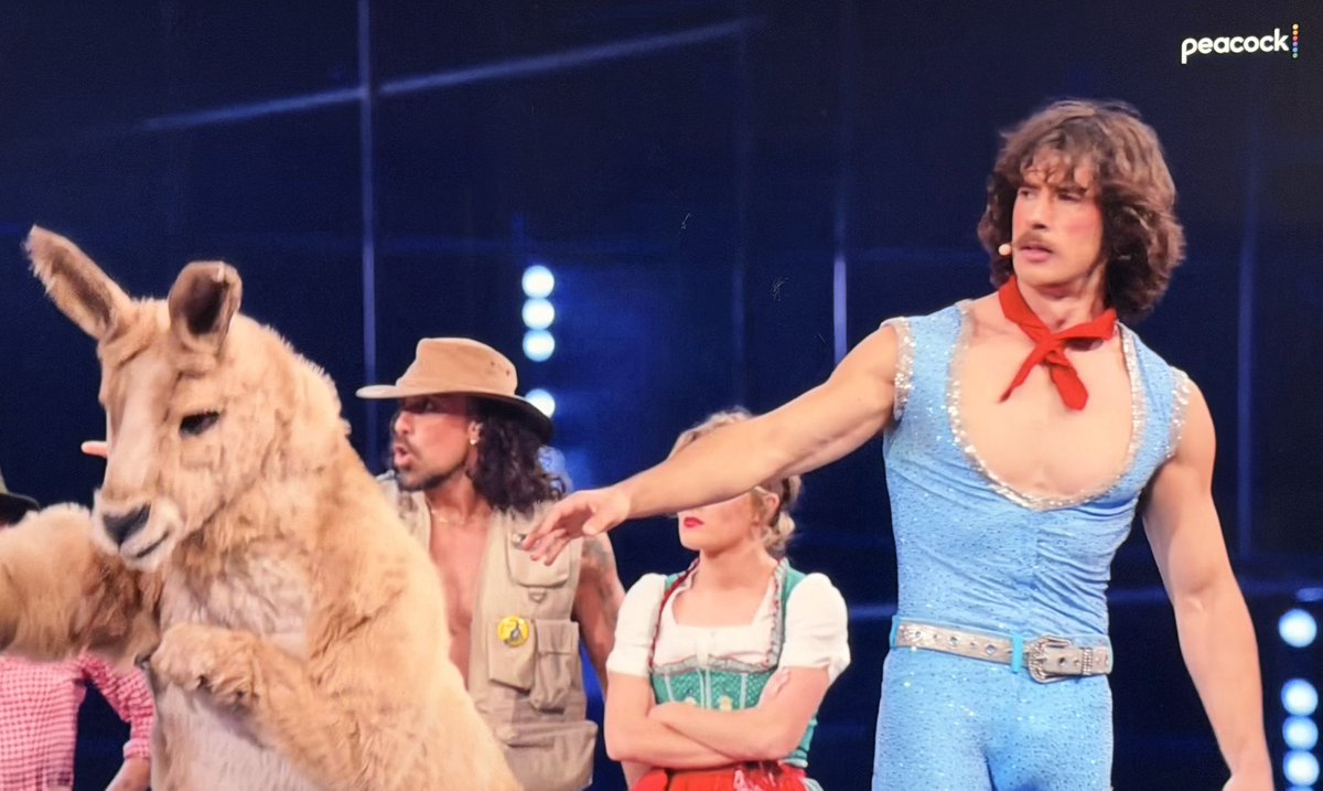 Dustin_Cone's tweet photo. Eurovision is watching a man called the ‘Milkshake Man’ wear a TIGHT sparkly body suit while wearing platform heals singing with his pet ‘kangaroo’ 
#Eurovision #Eurovision2026 https://t.co/XDsQj0gWUo