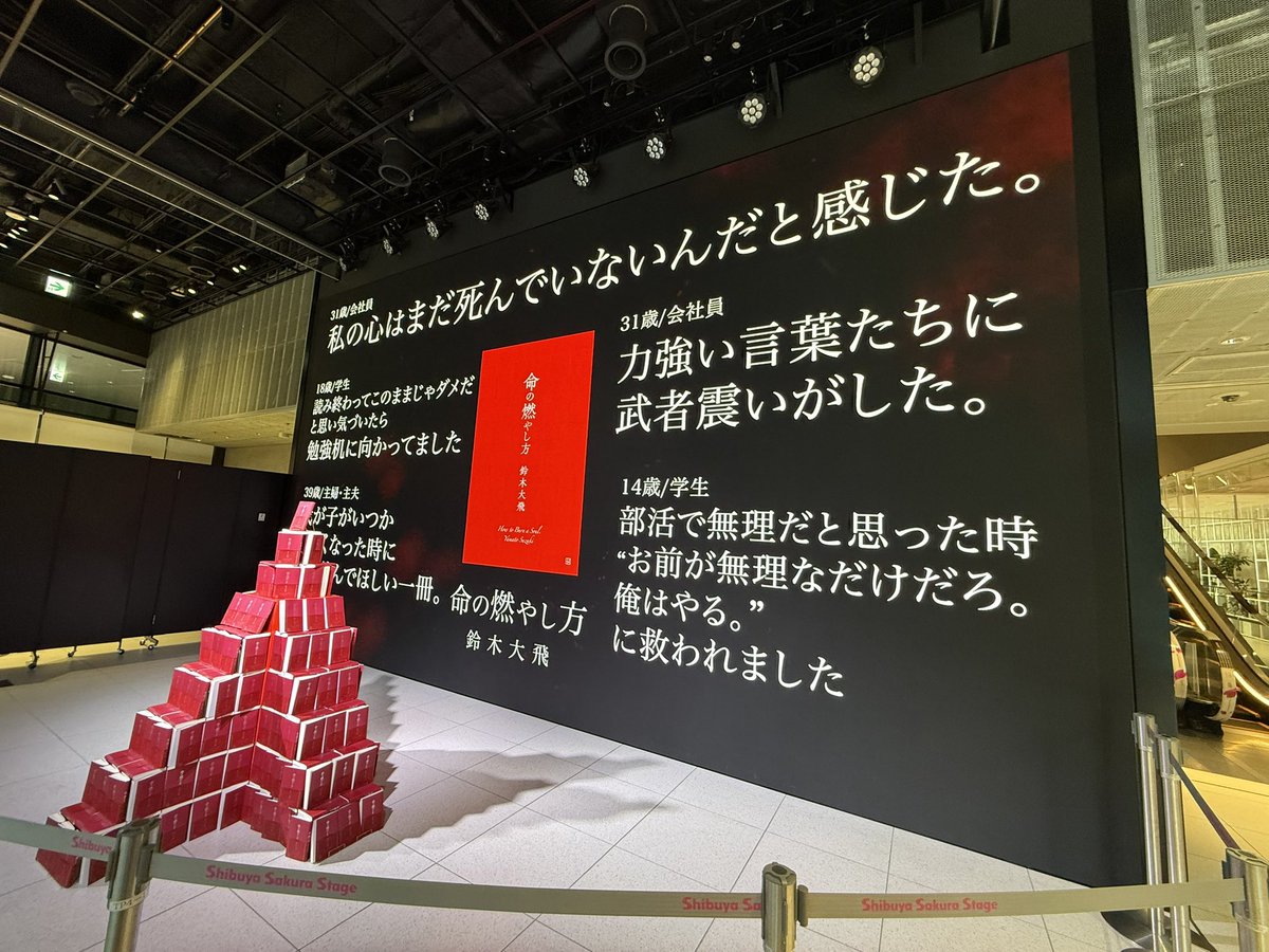 comsumitaso's tweet photo. 人だかりが人を��ぶ、ガラス張りで人が多く通る場所から見える命の燃やし方タワーと力強い言葉たちが流れる巨大スクリーン、圧巻。
〝目を引く〟という点において完璧。まだ手に取ったことのない人へも届け。 #命の燃やし方 
異空間感とファン得空間の対比が絶妙で天才でした。 https://t.co/fYyhdJ2huR