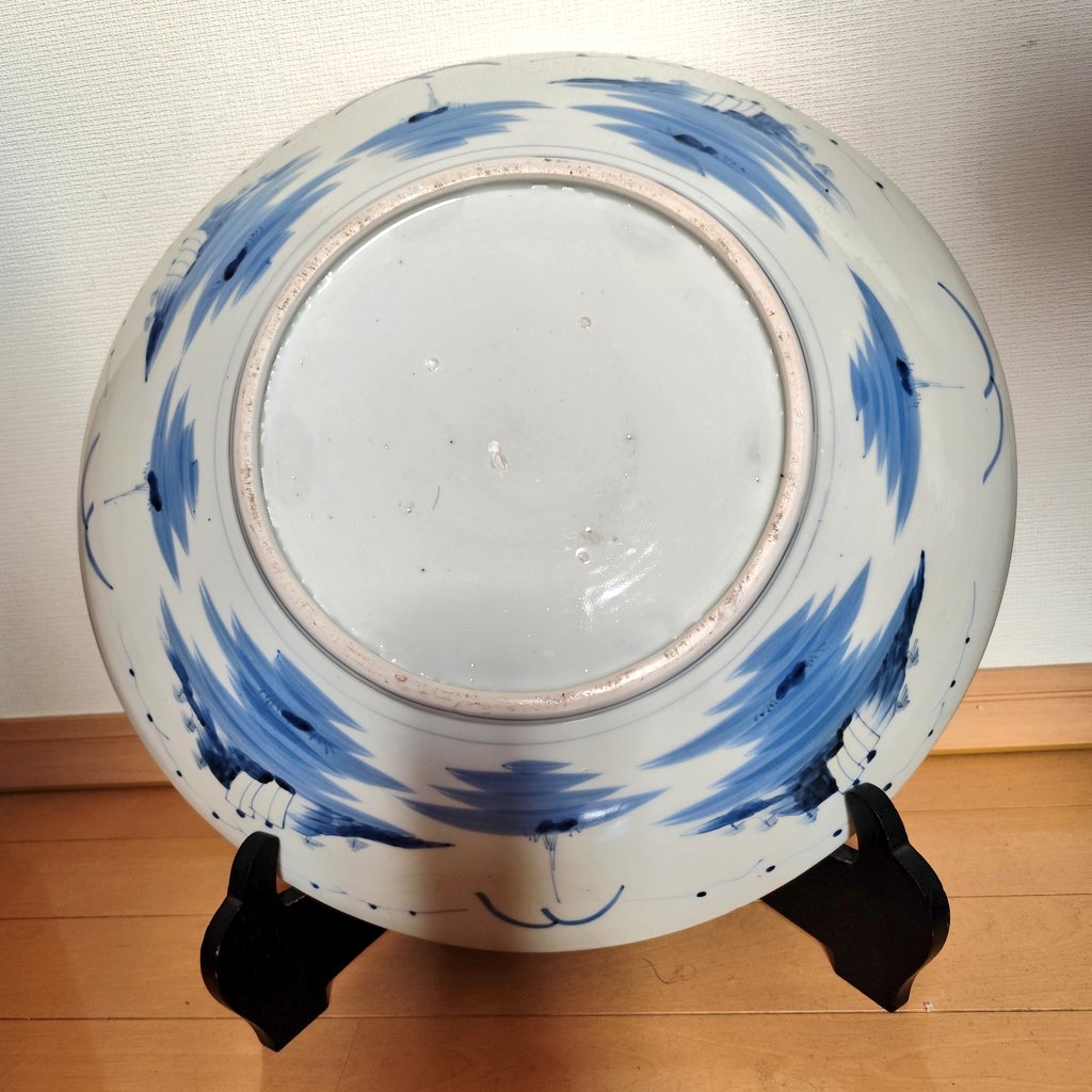 ume_43's tweet photo. 直径一尺五寸（約45cm）ほどある金襴手の大皿。おそらく明治期の作だろう。見込に色とりどりの牡丹、その周りには円窓の向こうに覗く菊花と扇窓に山水画が描かれている。裏面には水景に浮かぶ帆舟が八方に描かれ、高台内には目跡が残る。金箔の剥離が激しく、おそらく飾り皿というよりも実用品だろう。 https://t.co/hYZf9B1Xig