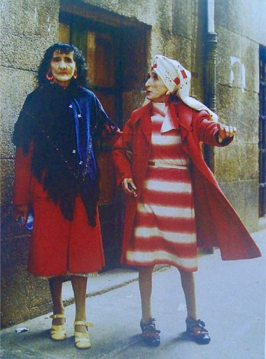 outsidersesp's tweet photo. Las Marías: el franquismo reprimió a estas hermanas en Santiago y ellas respondieron con vestidos chillones.

Maruxa y Coralia Fandiño sufrieron la represión franquista debido a que sus hermanos militaban en la CNT cuando estalló la Guerra Civil.

En Santiago de Compostela hay un símbolo laico, republicano y feminista que cada vez acapara más visitas. En el parque de la Alameda, en pleno centro, un grupo de visitantes se amontonan frente a dos coloridas estatuas que resaltan frente a la piedra y los símbolos religiosos que caracterizan a la ciudad. Se trata de la escultura de dos mujeres vestidas de amarillo y rosa que simulan caminar agarradas. Son las conocidas como las dos Marías.

Tras la imagen de las figuras se esconde una dura historia de represión política y exclusión social que gran parte de los turistas desconocen. Estas dos mujeres son Maruxa (1898-1980) y Coralia (1914-1983), hermanas pertenecientes a la familia Fandiño Ricart.

Rondaba el año 1932 y el clima de progreso y alegría envolvía la capital gallega. «La llegada de la República trajo una democratización de la vida cotidiana y un avance de libertades a las mujeres que se estaba empezando a conseguir», relata la historiadora Encarna Otero.

Las dos inseparables hermanas trabajaban en el taller de costura de su madre y tenían una costumbre que cumplían cada día: salir de su casa a las 12 de la mañana para recorrer, siempre juntas y cogidas del brazo, las calles de Santiago. Un paseo que terminaba a las dos del mediodía, hora en la que las señoras de la época se recogían, de ahí que también fueran apodadas como «As dúas en punto (las dos en punto)».

Todo cambiaría con la llegada de la Guerra Civil en 1936. En Galicia, aunque no llegó a estallar el conflicto bélico, se produjo un exterminio y persecución contra aquellas personas militantes de izquierdas y fieles a la República. En el período de guerra, fueron ejecutados unos 4.700 gallegos por motivos políticos y más de 28.000 sufrieron persecución policial.

Maruxa y Coralia vivieron de primera mano la represión franquista. Sus hermanos, Antonio, Alfonso y Manuel, eran sindicalistas de la CNT, por lo que ellos tuvieron que huir de Galicia o esconderse. Mientras tanto, la Policía franquista se presentaba en la casa familiar y amenazaba a las dos hermanas para que revelaran dónde se encontraban. Ante la negativa, comenzarían las vejaciones, torturas y abusos contra ellas. Fueron constantemente humilladas por la Policía del régimen en público, convirtiendo su vida en un infierno.

Las mujeres de la casa tuvieron que vivir las amenazas y controles de los falangistas a cualquier hora del día, siendo víctimas de una represión indirecta debido a la búsqueda de sus hermanos en el hogar familiar. «Las mujeres van a ser las primeras que estén sobre el control férreo de la Sagrada Cruzada; el control de la Iglesia fue terrorífico y en Santiago fue aún peor».

Ellas nunca revelaron dónde estaban sus hermanos, a pesar del constante acoso. La tortura no terminó incluso cuando años más tarde aparecieron todos ellos. Fueron señaladas como rojas, putas y locas. «Ya nadie acudía a su negocio, perdieron la clientela en el taller de costura, de forma que se quedaron sin empleo, su medio de sustento y supervivencia». Desde entonces, el hambre estaba presente en el día a día de sus vidas, sufriendo la férrea represión económica.

Maruxa y Coralia fueron completamente marginadas, víctimas de la exclusión social y la pobreza. «La sociedad las asumió como una normalidad anormal que ya formaba parte de la vida de la ciudad. Fueron calificadas como locas y aunque todo el mundo conocía su historia, nadie contaba qué era lo que realmente les había pasado», explica Encarna Otero, una de las primeras personas en difundir lo que habían vivido las Fandiño.

Una red de pequeños comercios de Santiago sí les ayudaba, pero ellas se negaban a recibir caridad. Por lo que los comerciantes les fiaban y los vecinos les dejaban dinero en los locales donde solían comprar. De esta forma, las hermanas pudieron sobrevivir a los peores años de la dictadura.

Las hermanas Fandiño Ricart pasaron a hacer una vida recluida, encerradas en su casa en un Santiago gris donde el terror de la dictadura se hacía notar. «Durante esos años detuvieron a uno de sus hermanos, estuvo en la cárcel y cuando salió sufrió tuberculosis y murió, por lo que fueron unos años en los que ellas se recluyeron en el ámbito familiar, seguramente porque la situación de la familia era terrible».

Habría que esperar hasta los años 50 para volver a ver a las dos hermanas paseando por la ciudad. Las Marías continuaron con sus paseos, como si no hubiese pasado más de una década. Manteniendo una actitud jovial, salían de casa a mostrar su disconformidad, una protesta silenciosa protagonizada por sus vestidos de colores chillones y sus maquillajes excéntricos que contrastaba con el ambiente frío y gris de la ciudad. Las dos se negaron a ser olvidadas y buscaban mostrar sus ganas de vivir tras lo sufrido los años anteriores.

Con mirada firme al frente y siempre agarradas del brazo, las Fandiño, ahora más mayores, más delgadas, casi desnutridas y sin dientes, emprendían su caminata hasta toparse con los estudiantes de Santiago con los que buscaban ligar como si fuesen una joven más, aunque muchas veces lo que recibían eran humillaciones, insultos o silbidos burlones de quienes las veían pasar. Maruxa respondía a todos los cumplidos, aunque también a los ataques de aquellos que se reían de ellas, mientras que Coralia se limitaba a sonreír a los saludos y cumplidos.

Para muchos eran unas «viejas locas». Sin embargo, detrás de su comportamiento se escondía el sufrimiento, la tortura y la exclusión que sufrieron durante años. Un trauma que provocó que se refugiasen en la época de su vida en la que fueron felices. «En su locura ellas se instalaron en su vida de jóvenes, seguían comportándose como las veinteañeras que eran antes de la llegada de Franco»…
