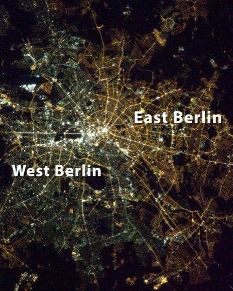 SeeOutThere's tweet photo. Pad Berlinskog zida možda se dogodio još 1989. godine, ali tragovi podele grada ostali su vidljivi dugo nakon što su te betonske barijere nestale. Jedan od najzanimljivijih primera mogao se videti čak i iz svemira.
Godinama nakon ujedinjenja, astronauti koji su fotografisali Berlin noću primećivali su jasnu razliku između nekadašnjeg istočnog i zapadnog dela grada. Razlog je bio iznenađujuće običan: ulična rasveta. Istočni Berlin je uglavnom nastavio da koristi stare natrijumske lampe koje su bacale toplu narandžastu svetlost, dok je zapadni deo grada više koristio beličastu fluorescentnu i živinu rasvetu. Posmatrano iz orbite, taj kontrast stvarao je tanku, ali prepoznatljivu liniju kroz grad.
To je bio podsetnik da istorija ne nestaje preko noći. Politički sistemi mogu da se uruše u jednom trenutku, granice mogu da se otvore, zidovi mogu da budu srušeni pod udarcima mase ljudi sa čekićima, ali infrastruktura, navike, ekonomija i identiteti oblikovani tokom decenija ostaju mnogo duže.
Danas je veliki deo te vizuelne podele nestao kako Berlin prelazi na LED rasvetu i savremenije tehnologije. Ipak, te fotografije i dalje imaju snažnu simboliku. Pokazuju da gradovi, baš kao i ljudi, nose svoja sećanja ispod površine dugo nakon što vidljivi ožiljci nestanu.