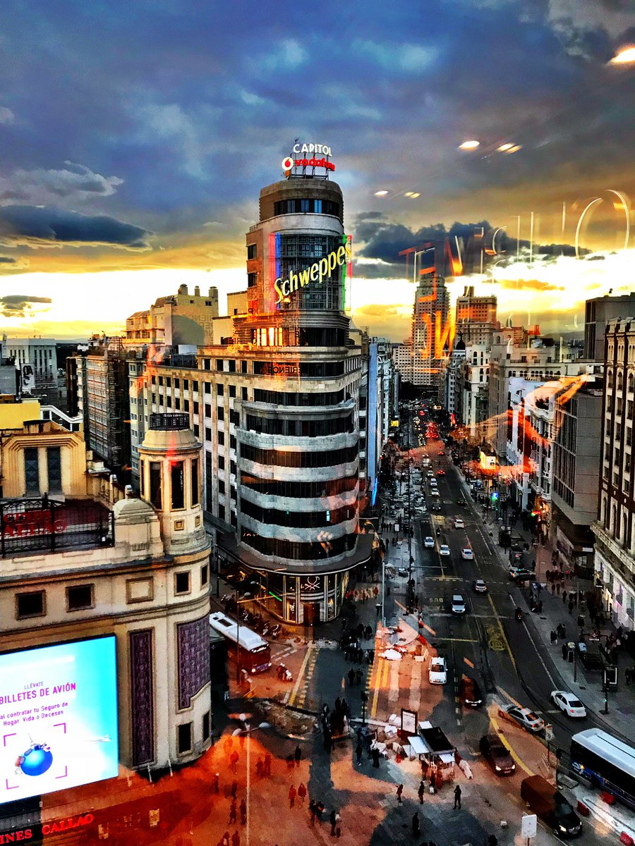 andresmadrigalg's tweet photo. Hubo un tiempo en que Madrid se conjugaba en presente de barrio. Un tiempo en que cruzar de una acera a otra de la Gran Vía no requería el instinto de supervivencia de un náufrago en un océano de maletas de mano y selfis clónicos. Aquel Madrid de hace 40 años se construyó con un diccionario propio que nacía en las barras de aluminio y moría en los portales. Hoy, uno camina por la Red de San Luis y se descubre extranjero en su propia memoria, envuelto en un murmullo cosmopolita e idiomas de todas partes. Te asalta entonces la gran pregunta muda: ¿en qué momento exacto Madrid dejó de pertenecer a los madrileños?
No es esta una queja contra el forastero. Esta ciudad siempre tuvo el orgullo legítimo de no pedir el pasaporte a nadie; aquí se era de Madrid a los diez minutos de bajarse en Atocha, compartiendo el espacio entre los de siempre y los que acaban de llegar.
las Fiestas de San Isidro parecen librar una batalla sorda por no perder el alma. El calendario marca el día del patrón, pero la Pradera se llena de una energía renovada donde el menú popular muta. Aquellas verbenas que antes olían exclusivamente a gallinejas, entresijos, morcilla frita y raciones de bravas compartidas en mesas de formica, conviven ahora con otros manjares. Es una evolución natural donde el pasado y el presente se dan la mano.
Para escuchar el Madrid auténtico, el que todavía arrastra la «z» al final de las palabras con orgullo tabernario, hay que huir de la almendra central. Los madrileños de Madriz no han desaparecido; simplemente la «z» ha viajado y se ha adaptado a la geografía actual, buscando nuevos refugios en los márgenes de los mapas oficiales. Incluso en barrios como Vallekas, con su «k» de resistencia, el aguacate le ganó la vez a la banquetera del torrezno en total armonía. 
Hoy, el uso de los viejos modismos revela de inmediato la edad de la memoria de quien los pronuncia. Decir “chupa” evoca el invierno de los ochenta, cuando la “peña” o la “basca”no quedaban para un café de avena por WhatsApp, sino haciendo cola en las cabinas de teléfono, con monedas de veinticinco pesetas en la mano, para citar a las parejas en una esquina. Quedaban para tomar unas “cañas” o unos “penaltis” de cerveza apuntados con tiza en calles míticas como Fuencarral, antes de ser peatonal, en la bohemia de Malasaña, o bajando por Montera y Atocha. La economía del día a día se movía entre “talegos”, “melones” y escuchando música en el “Loro” del “colega”, mientras se buscaba un “curro” y se evitaba a cualquier “notas” que te metiera un “marrón”. En la periferia, esa jerga se ha hibridado. Los nietos del “mola un huevo” mezclan ahora la «z» con palabras del “trap, Bro, Guey o chévere”, expresiones latinoamericanas que manteniendo la misma función: marcar la identidad del barrio.
Se echa de menos la cotidianidad ruidosa de los pubs pequeños de Argüelles o los bares de desayuno de la calle Alcalá, donde el eco de la mañana se mezclaba con los golpes secos de manillar del futbolín y las monedas que daban paso a otra partida. Aquellos templos del humo y la confidencia han sido devorados por la uniformidad. El naufragio es silencioso pero constante: los míticos salones de billar se han convertido, al igual que algunos cines, en hamburgueserías o restaurantes temáticos. ¿Adónde han quedado lasluces tenues y los tapetes verdes con lastizas azules en los dedos?
Cierra el bar de siempre, la librería de viejo y la zapatería de barrio con su olor a pegamento y cuero. Si hoy Sabina o Flores tuvieran que reescribir su himno, la letra tendría que decir que “las franquicias viajan en ascensores rotos” y “los edificios mueren por un piso turístico”. Madrid se nos ha vuelto una ciudad escaparate, hermosa pero transformada. Nos queda la militancia de cruzar el río para buscar el Madrid que se resiste a morir entre “las tontas y las listas”de la Pradera de San Isidro, demostrando que el espíritu de la ciudad sigue siendo inquebrantable.
Feliz San Isidro, Gatos/as, Chelis y Chulapos/as.