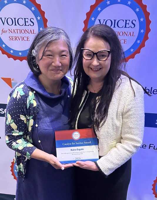 Two people smiling with plaque "Catalyst for Service" award.