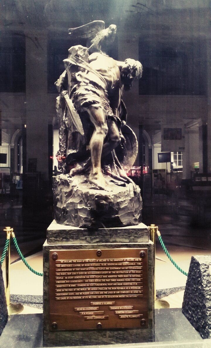 timelesscolours's tweet photo. Below Sheppard’s Cú Chulainn in the GPO stands the Proclamation of the Irish Republic with the names of the seven signatories.

Something deeply poetic in that choice. A statue born from the Celtic Revival’s fascination with myth, sacrifice and heroic memory would later become... https://t.co/J6uFSNIN25