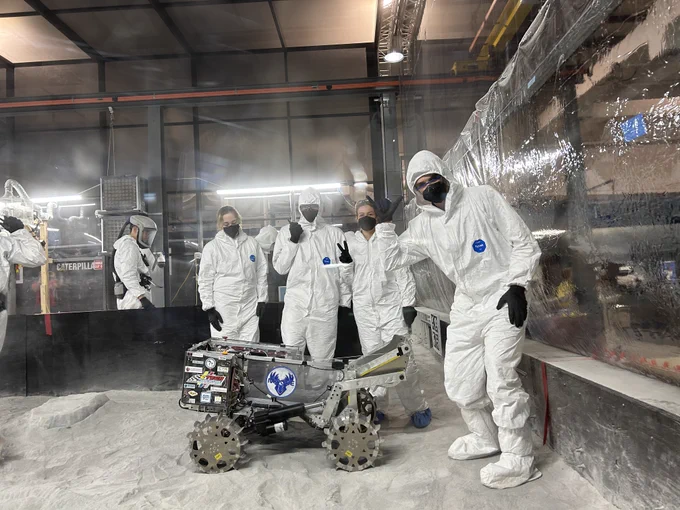 Four Michigan Tech students pose in protective gear with their lunar rover 
