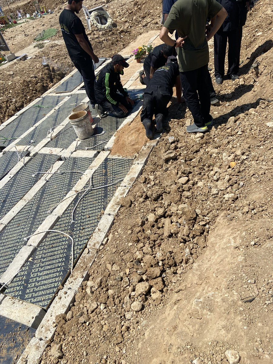 HalaJaber's tweet photo. They call it a “وديعة”.

A deposit.

That is the word many Lebanese families are now using for the temporary burial of loved ones who cannot be taken home because of the war.

In English, the word sounds cold & administrative. A deposit is something placed somewhere temporarily until it can be reclaimed.

So much bureaucratic connotation in a word for something so intimate.

A deposit.

As though she were luggage.
Or a document.
Or an item being stored.

But in Arabic, وديعة carries another meaning too. It is something entrusted. Something left in safekeeping. Something precious that is being held until it can be returned.

And yet, when we are talking about a mother who has just died, it feels unbearable.

Because no daughter wants to say:

“We are placing my mother as a وديعة.”

It sounds as though death itself has become temporary storage.

As though war has reached so deeply into ordinary life that even burial has been put on hold.

These days, because of the war, many Lebanese families are having to place their loved ones as وديعة.

Not because they want to.

Because they have no choice.

Roads are inaccessible. Villages remain under threat. Entire areas are subject to bombardment &  displacement orders. Families can no longer safely reach the towns & villages where generations before them were buried.

Last week, when my mother died, we became one of those families.

Taking Siran back to Nabatiyeh to lay her beside my father, where she always asked to be buried, was simply a mission impossible.

So instead, my brother & I followed the vehicle carrying her coffin to a temporary burial ground.

There was no familiar procession.

No gathering of relatives.

No prayers in the Hussainiya before departure.

No final journey home.

Only a quiet drive.

A Sheikh offered prayers over her body. Strangers gathered around us & prayed alongside us. Then a few men carried her towards a section of the cemetery reserved for what people now simply call the deposits.

A small concrete space had been prepared. Inside it sat a simple wooden coffin-sized box built to the exact dimensions of the concrete cavity, designed to facilitate transfer in the future.

Another prayer was said.

The soil was placed over her.

Around us, women wailed over other graves. A microphone carried prayers for someone else’s dead. Flags fluttered above nearby tombs. The whole scene felt surreal, suspended somewhere between mourning & administration.

Then one of the men looked at us & said:

“Write this down. Memorise this number.”

3/5.

The fifth coffin in the third row.

That is where my mother now lies.

A small stone bearing her name will eventually be placed there so that one day we can find her again & take her home.

Home.

What a simple word.

For centuries families buried their loved ones beside parents, spouses, ancestors & neighbours. It was a final act of belonging.

Today many of us are forced to say:

“Not yet.”

“For now, we leave them here.”

“We will come back for them later.”

War takes many things from people.

Homes.

Safety.

Certainty.

But I never imagined it would take this too.

That even in death, my mother could not be laid to rest beside the man she loved & always called ‘the best of men.’

For now, Siran remains a وديعة.

Entrusted.

Held.

Waiting.

And one day, God willing, when the roads are open, the bombs have stopped, & Nabatiyeh is once again reachable, we will take her to where she always wanted to be.

Beside my father.

Where she belongs.
