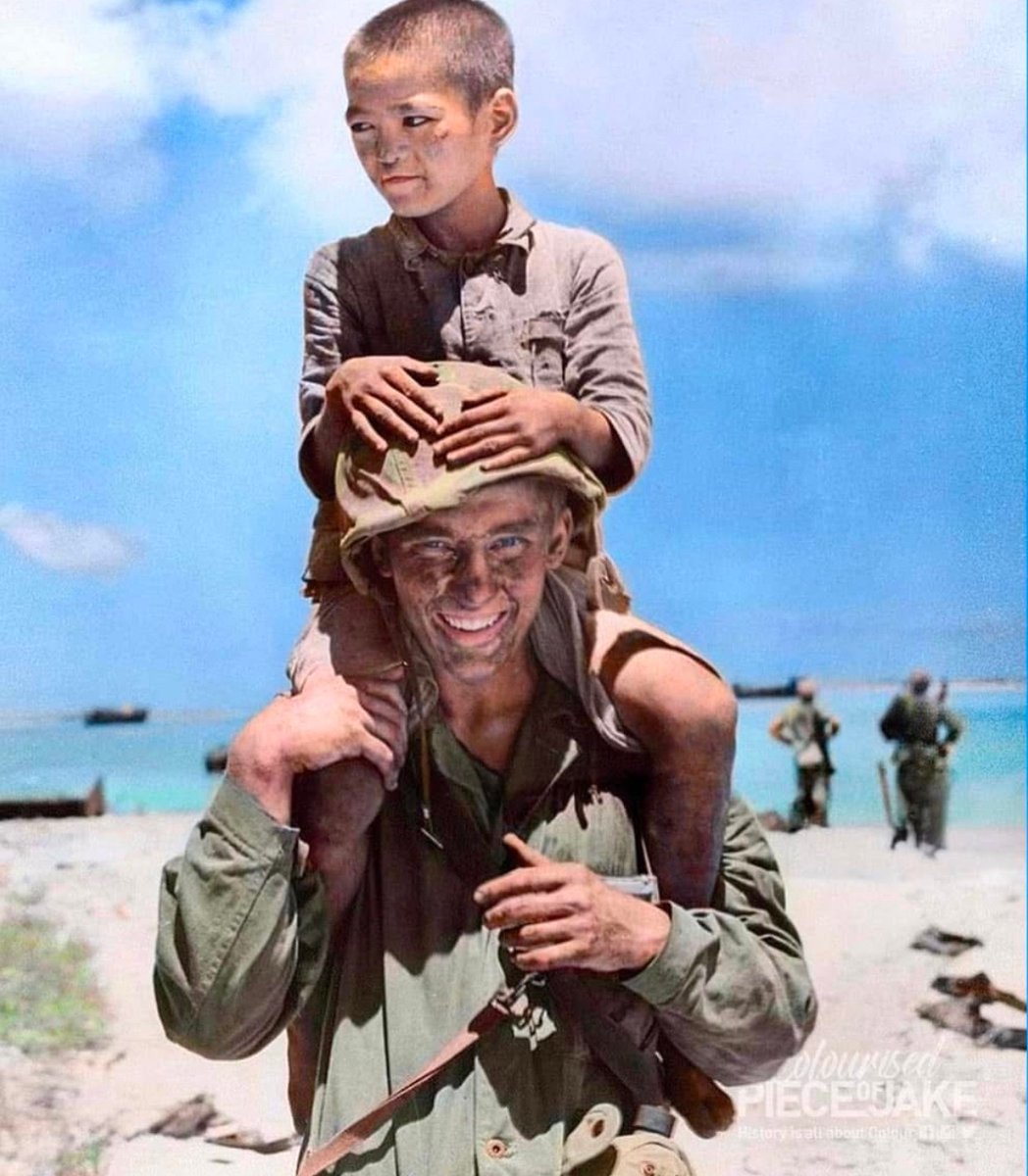 Jason_R_Burt's tweet photo. In June of 1944, a friendly Marine gives a young boy a ride on his shoulders days after the fighting on Saipan ended. 🪖

@PieceJake
 on the colorization 🎨 https://t.co/h6itjuRrF2
