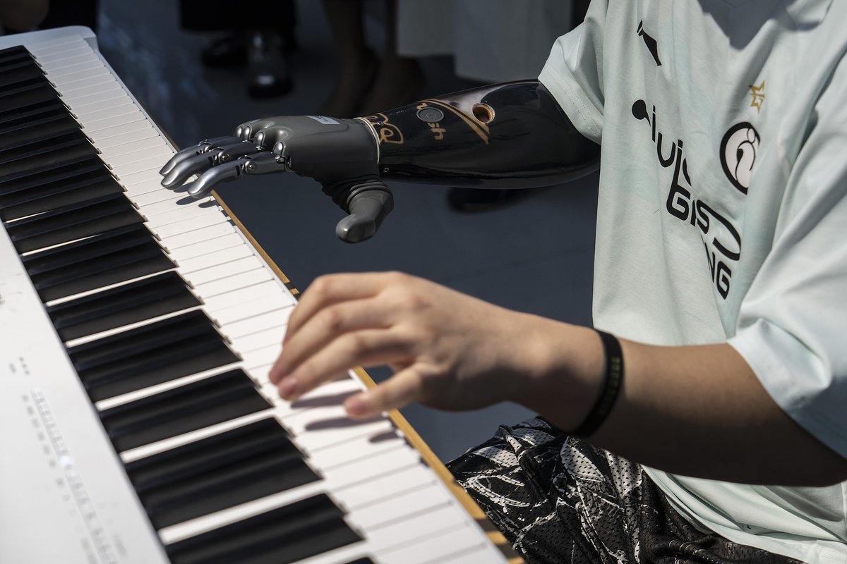 ChinaDaily's tweet photo. What if you could play the piano just by thinking? 🎹 In #Hangzhou, #Zhejiang province, a worker plays piano keys with a bionic hand controlled by his mind. #BrainCo's prosthetic reads muscle signals without surgery. It offers a precise grip and a lightweight design. As #China's robotics industry booms, more lives will soon feel this #technology. 🦾