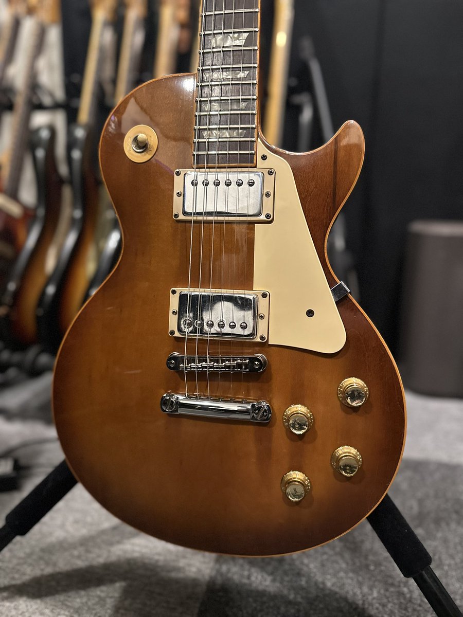 kkkzzzyyy's tweet photo. 『先生、買っちゃいました…。』

と言いながら、ギターレッスンの生徒さんがニコニコしながら見せてくださった1976年製のGibson Les Paul🎸

そういえば前回のレッスンで、レスポールの魅力を熱く語りながら、あれこれリフを弾いていたなと思い出しました（笑）。その後、生徒さんはいてもたってもいられなくなり、そのままレスポールを探しに行ったそうです。

こういう話、なんだか嬉しいんですよね☺️

自分が好きなギターの魅力を伝えたことで、誰かが心を動かされて、新しい一本との出会いにつながる。ギター講師冥利に尽きます。

今回購入されたのは76年製。僕自身、70年代後半のレスポールはそこまで深く触れてこなかったのですが、これがなかなか面白い一本でした。

どうやら元々はLes Paul Deluxeだった個体らしく、ミニハムバッカー仕様だったものをフルサイズのハムバッカーへ交換。パーツ類もいろいろ変更されているようです。

そしてこの年代らしいポイントとして、3ピースのメイプルネック。

メイプルネックというと、どうしても「硬い」「明るい」「カチッとしている」というイメージを持ちがちですが、実際に触ってみると、そこまで単純ではないんですよね。

サウンド的には、どこか切っ先が丸い。鋭すぎず、でも芯はある。メイプルらしい輪郭は感じるのに、倍音は抑えめで耳に痛い方向には行かないというか、思っていたよりも少し柔らかい場所に着地している印象でした。

このあたりが、ハードロックやメタルのイメージとも結びつきやすい70年代レスポールの面白いところなのかもしれません🔥

そして、何より目を奪われるのがこの色！

とにかく焼け方が凄い。

長い年月をかけて飴色に変化したトップの色味が本当に美しくて、「これが決め手でした」とおっしゃるのもよく分かります。

確かにこの焼け方は半端じゃない。新品では絶対に出せないし、Murphy Labでもなかなか再現できないかもしれない。もしかしたら、この年代だからこそ生まれた色なのかもしれませんね。

ナイスチョイスだと思います！

そして何より、その行動力が最高です（笑）。

おめでとうございます🎉
引き続きギターを楽しんでください！🎸✨