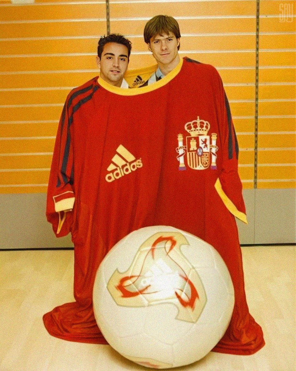 Barca_Archive's tweet photo. Xavi Hernández and Xabi Alonso in an oversized Spain National Team shirt. Promotional shoot for Adidas, 2002. https://t.co/Q99RJ06xaR