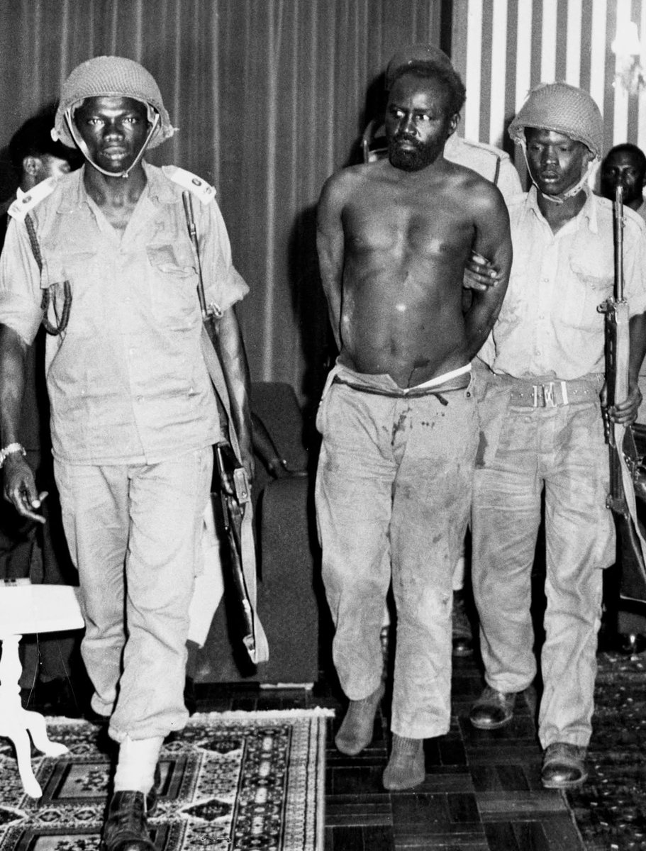 africatodayMG's tweet photo. Pictured here is Alex Ojera, who served as Minister of Broadcasting and Tourism under President Milton Obote, being escorted to President Idi Amin following his capture.  

In September 1972, Ojera was among Obote’s allies who attempted to return to Uganda covertly to reinstate Obote in power. The group was detained by soldiers loyal to President Idi Amin.