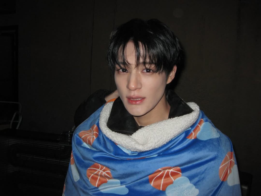 Jenoolee's tweet photo. Wrapped in clouds and basketballs, pretending I’m not tired of being strong all the time. The room is dark but I’m glowing in my own soft way. Sometimes comfort looks like a blanket, sometimes it looks like choosing peace over performance. https://t.co/sUwgRVdNjB