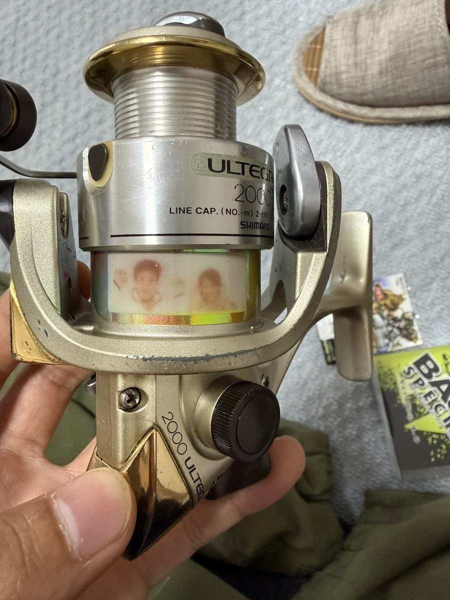 Ramen_ch_Kuwa's tweet photo. 越してきたばかりで釣具が一切ないので中古で2000円で売ってた格安の化石SHIMANO ULTEGRAを購入。
ラインを巻き付けようとしてたところ謎の写真発見…なんだこれは笑 https://t.co/qo5qUsKsJ1