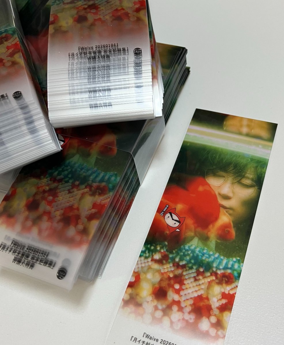 info_a_g's tweet photo. 【アプレゲール別冊『Waive 20260104』＆『月イチ杉本善徳 完全記録集』W購入特典完成！】杉本善徳＆鉄ぱいぷ君のコラボ(?)しおりが出来上がってまいりました。紙ではなく、クリアファイルのようなPPシートのしおりです。アンニュイな表情と金魚が半透明の素材とマッチして、なかなかよい感じでは。 https://t.co/XvMDjeJ2Eu