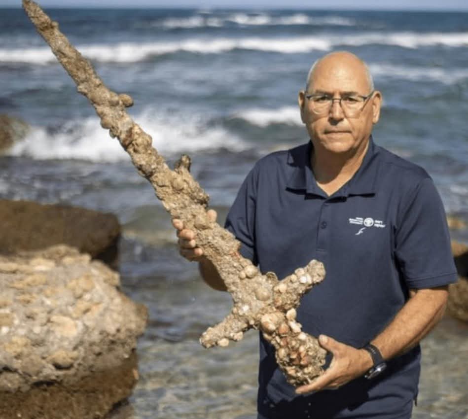 histories_arch's tweet photo. A 900-year-old Crusader sword that was found in 2021 on the bottom of the Mediterranean by a scuba diver... 

The iron sword, measuring about 3 feet (1 meter) long, was discovered by diver Shlomi Katzin near the ancient port city of Atlit after shifting sands exposed artifacts on the seabed.

Archaeologists from the Israel Antiquities Authority identified the weapon as a Crusader-era sword dating to roughly the 11th–13th centuries. The region was a major battleground during the Crusades, when European Christian kingdoms established and defended territories in the Levant. Atlit itself was home to the formidable Crusader fortress known as Château Pèlerin, built by the Knights Templar in 1218.

Although heavily encrusted with marine organisms after centuries underwater, conservation experts determined that the blade and hilt remained remarkably well preserved beneath the deposits. The sword was carefully recovered and stabilized to prevent deterioration once exposed to air.

Thousands of medieval ships passed along this stretch of coastline, and underwater surveys have uncovered anchors, pottery, weapons, and cargoes spanning more than 4,000 years of maritime history, making it one of the richest underwater archaeological regions in the eastern Mediterranean.