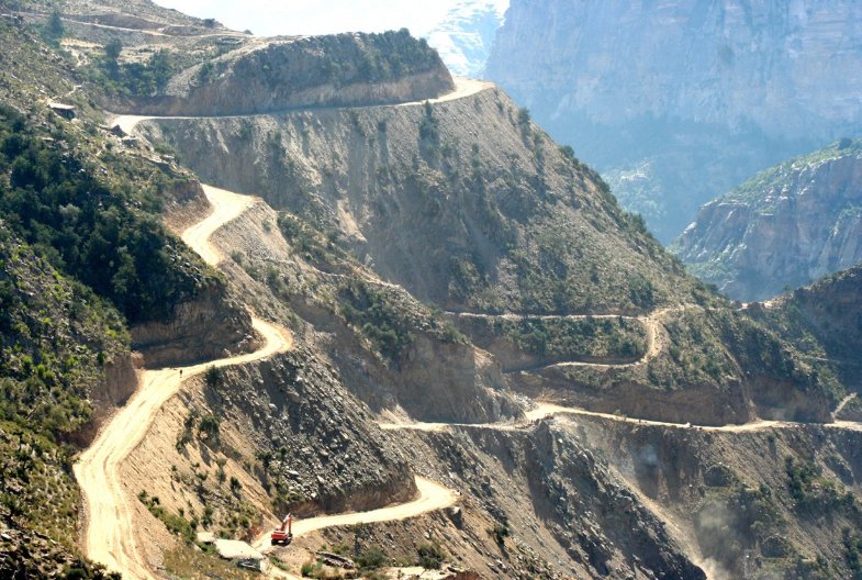 shabait's tweet photo. Paving the Path to Social Justice: Eritrea’s Post-Independence Road Construction
By: Mussie Efriem

When Eritrea was liberated on May 24 1991 following a long armed struggle, it immediately faced the monumental task of reconstruction and nation building. To undertake this formidable task, the government has prioritized sustainable national development designed to secure a bright and prosperous future for generations to come. Central to this vision was a commitment to equitable growth across the entire country, ensuring equal opportunities and the inclusive provision of resources for the whole population.

To realize this inclusive goal, the government has committed itself to the core principle of social justice by allocating equal opportunities and essential public services to every citizen, regardless of their geographic location. This foundational principle transformed national recovery efforts into a structured campaign for civic well-being, ensuring that healthcare, education, and clean water are treated as basic human rights.

To ensure the successful realization of these nationwide goals, the Eritrean youth have been placed at the very center of the country’s development programs. Under national initiatives, thousands of young men and women regularly undergo technical and vocational training at centers across the country. Students acquire critical skills in essential fields such as technical drafting, heavy machinery operation, building technology, and infrastructural engineering. Armed with essential technical knowledge and skills, the empowered workforce has been crucial in transforming the country’s domestic transport network.

Transportation infrastructure is critical in ensuring access to essential human needs and opportunities within a society. Beyond its economic use, transportation bridges socioeconomic gaps, directly linking diverse communities to healthcare, quality education, employment centers, and civic spaces. Ultimately, investing in reliable roads, bridges, and public transportation systems is an investment in social justice and community resilience, transforming society through collective well-being.

Communities that were formerly isolated and cut off from timely medical and emergency services due to lack of transport infrastructure prior to Eritrea’s independence have been fully integrated into the national network through newly constructed roads. This widespread expansion of roads has converted arduous journeys that took days into trips that take just a few hours. A notable testament to this milestone is the critical coastline route linking the strategic port cities of Massawa and Assab. The journey used to take two to three days over harsh terrain, but it now takes not more than a day.

Another significant achievement of the post-independence era is the modernization of the strategic Barentu-Tessenei highway, a route that goes as far as neighboring Sudan. In the first few years following Eritrea’s independence, this vital road was rather difficult to navigate; however, with the government’s timely intervention, it was transformed into a fully modernized, asphalted route that facilitates efficient cross-border connection. The construction of the Serejeqa-Shebah road, built under the Warsay Yikealo development campaign, stands as another monumental product. Carving a path through some of the country’s steepest, most treacherous mountain escarpments required profound sacrifice and dedication. This magnificent road cuts through the breathtaking Eritrean Green Belt, a beautiful ecological zone that is one of the country’s thriving natural habitats and premier tourist attractions celebrated for its rich and diverse fauna and flora.

In addition to these major arteries, the government has achieved tremendous progress in the country’s Western lowlands by converting impassable tracks into reliable transport routes. This includes the road from Akurdet to Sawa, which was upgraded with a combination of modern half-asphalt and high-quality, compacted soil layers. Similar infrastructural upgrades have fundamentally transformed roads across the Western lowlands, replacing difficult journeys with vastly improved networks connecting Keren to Geleb, Afabet to Felket, Afabet to Nakfa, Akurdet to Grmayka, Tessenei to Omhajer, and Akurdet to Kerkebet.

Alongside the eastern escarpments, the construction of the iconic Egila-Demhina road stands as a monumental engineering achievement linking Adi Keyih subzone to Foro subzone. Penetrating through cliffs and once-impenetrable mountains via Robrobya, Karibosa, and Wi’a, this new passage replaces the old, highly circuitous Nefasit-Ghinda’e- Gahtelay route, enormously cutting the original travel distance from 300 kilometers to just 120 kilometers.

Building on these successes, ongoing development works are advancing rapidly along the vital Nefasit-to-Serha route, from Dekemhare to Tera Emni and from Adi Quala to Enda Gergis. Furthermore, ongoing projects are shaping the connection from Forto Sawa to Tessenei via Adibara and Tamarat. This aggressive blueprint for countrywide social justice has trickled down to the most isolated populations, remarkably granting full road connectivity to around 90 villages in Mai Mine subzone that previously lacked any form of access to transport.

Some of the world’s most monumental infrastructures have been engineered and executed by military workforces. Prime historical examples include Egypt’s iconic Aswan High Dam, which successfully tamed the Nile River to provide electricity and irrigation, and the Panama Canal, an engineering marvel constructed under the direction of the United States Army Corps of Engineers to redefine global maritime trade permanently. Utilizing a disciplined, highly organized defense force for public works allows nations to mobilize a large-scale workforce rapidly. This proven strategy of civil-military intervention demonstrates how state institutions can use the military, during peacetime, to serve as primary catalysts for national recovery, turning structured labor toward the vital tasks of building dams, expanding highways, and constructing the foundational frameworks necessary for long-term economic sovereignty.

Similarly, as part of the Warsay Yikelao campaign, members of the Eritrean Defense Forces have served in the nationwide development works, translating their disciplined organization into historic civil engineering achievements. A prime manifestation of this is the road project that stretches from Gulo to Talha Ner’e, Senafe subzone. This vital route cuts across the challenging Emba Soira mountain range, passing through the nation’s highest elevation at approximately 3,018 meters above sea level. In parallel with these rural connections, urban infrastructure have undergone significant modernization in the post-independence years, notably exemplified by the ongoing construction of the strategic Asmara ring road. Once completed, this critical infrastructure will form a comprehensive loop around the capital, seamlessly redirecting heavy trucks around the outskirts, drastically reducing inner-city congestion and minimizing municipal road wear.

In addition to this extensive road network, hundreds of modern bridges have been constructed across the nation over the past 35 years of independence. These crucial structures were erected through the dedication, resilience, and unyielding determination of Eritrean construction companies. By bridging these physical divides, they have not only prevented hazardous washouts during the heavy rainy seasons but have also permanently secured the safety and continuity of national transit. This monumental bridge-building campaign stands as a defining symbol of Eritrea’s self-reliance, demonstrating that the country’s domestic workforce has the technical capacity and stamina to resolve its most complex infrastructure challenges independently.