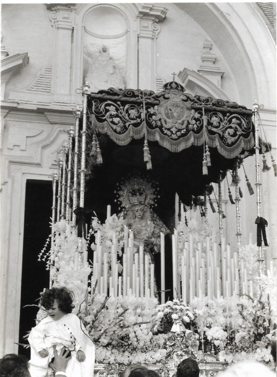 hdadlaestrella's tweet photo. ⭐¿Sabías qué? 

En 1975 María Santísima de la Estrella procesionó con la toca conocida como de «Juanita Reina». Esta toca de sobremanto, diseñada por Juan Pérez Calvo y ejecutada por Concepción Fernández del Toro, fue regalada por la citada artista en 1950 a la Virgen de la Esperanza. 

Desde el año anterior, María Santísima de la Estrella procesionaba con manto liso al encontrarse el suyo en mal estado de conservación. Posiblemente, por mediación de Antonio y Pepe Garduño, con objeto de enriquecer la visión, se solicitó el préstamo de una toca de sobremanto bordada. La propia, no llegaría hasta 1977. El préstamo con la querida @Hdad_Macarena ya se había producido años anteriores por los hermanos artistas, luciendo la Virgen de la Esperanza el terno de hebrea de nuestra Virgen hacia los años 60 del pasado siglo. 

Encontramos a la Virgen saliendo de la @SanJacintoPQ, con el ambiente popular, devocional y de barrio que rodea nuestra hermandad. Entre otros elementos de la vestimenta de la Virgen, destaca la ausencia de puñal, siendo sustituido por sus mariquillas durante años de la década de los años 70. En el centro, luce el broche de Emilio Armenta con el antiguo escudo de la hermandad en esmalte. Luce saya de bordados toreros, estrenada en 1969.

María Santísima de la Estrella, ruega por nosotros.

📷Fotos Justo Rodríguez Nieto (Archivo Jesús García)/Hdad. de la Macarena

#HistoriaenlaEstrella