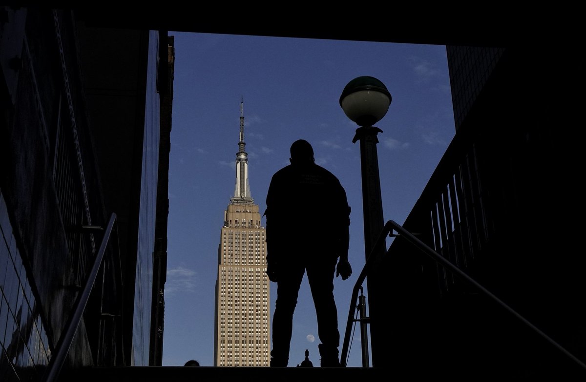 GaryHershorn's tweet photo. People enter and exit a subway station on 34th Street as the sun sets on the Empire State Building and an 89 percent illuminated moon rises behind it in New York City, Wednesday evening #newyork #newyorkcity #nyc @EmpireStateBldg #sunset #moon https://t.co/n5aVEQUGB8