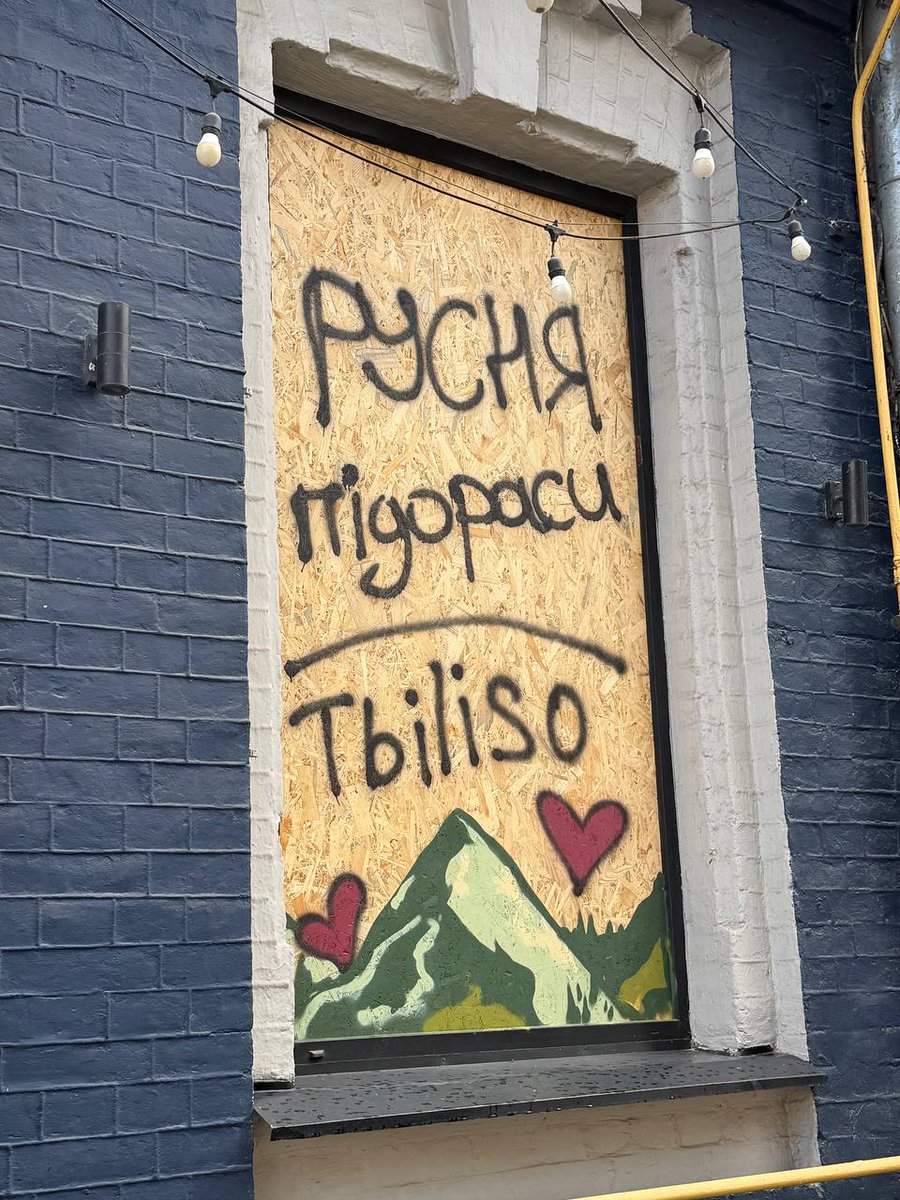 NAFOvoyager's tweet photo. Kyiv.  A Georgian restaurant called Tbiliso was damaged in the latest russian strike.

They boarded up the broken windows with plywood… and kept serving people. 

“Putin is a huilo.
russians are assholes.”

This is Ukraine.
We don’t break.
We just get harder.
🇬🇪🤝🇺🇦 https://t.co/1iz6ckK7SN