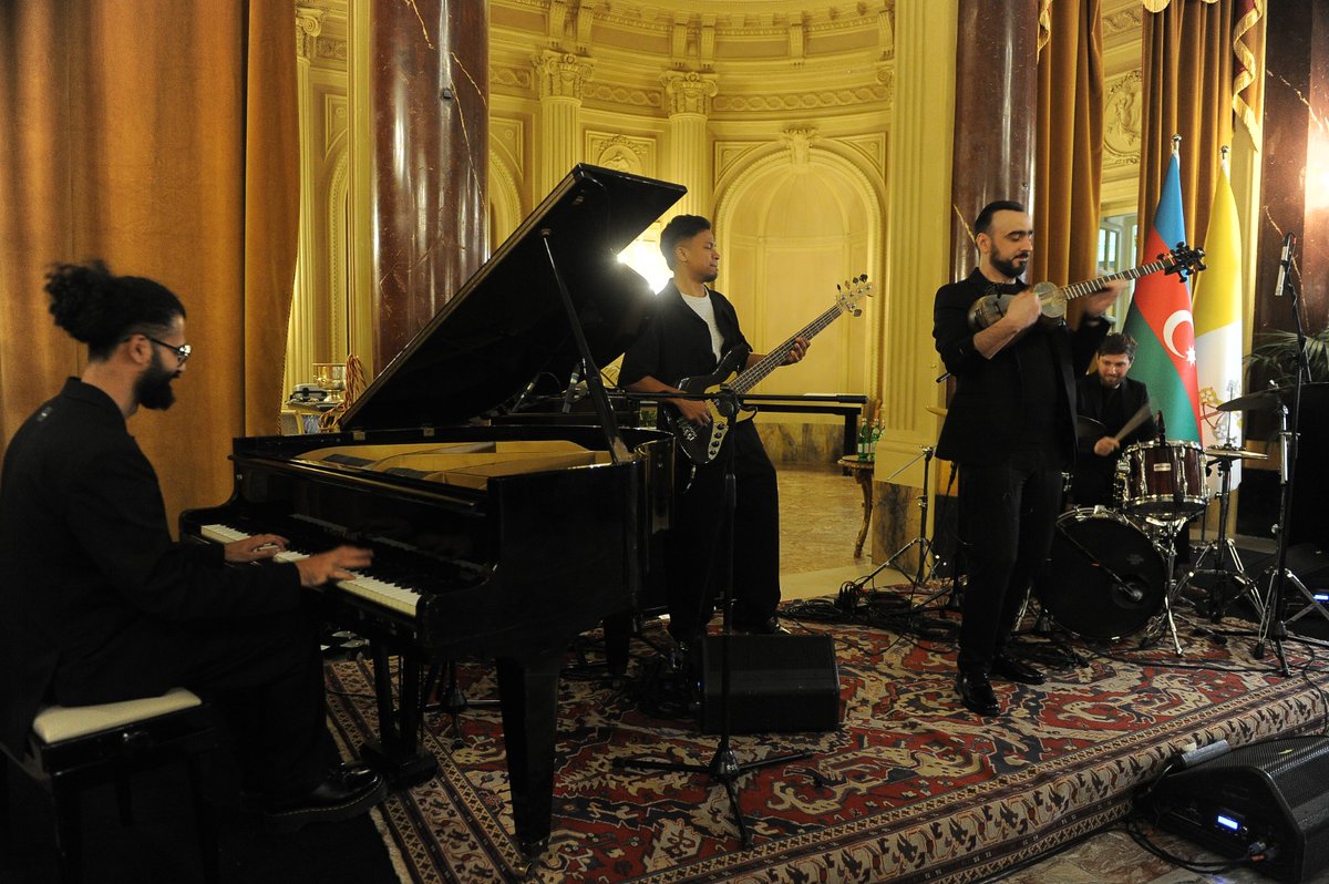 AzEmbVatican's tweet photo. Il 26 maggio, presso l’Hotel The St. Regis di Roma, si è svolto un evento celebrativo dedicato a una ricorrenza fondamentale della storia dell’Azerbaigian: il 108º anniversario dell’Indipendenza, che segna la proclamazione della prima repubblica democratica e laica del mondo musulmano. 
A fare i suoi saluti l’Ambasciatore della Repubblica dell’Azerbaigian presso la Santa Sede, S.E. Ilgar Mukhtarov, che ha accolto il numeroso pubblico composto da rappresentanti del Vaticano, con la partecipazione dell’Arcivescovo Mons. Paul Richard Gallagher in qualità di ospite d’onore, rappresentanti del corpo diplomatico, del mondo dell’istruzione, dei media e della comunità azerbaigiana.  L’Ambasciatore ha innanzi tutto ricordato come questa giornata sia nel cuore del popolo azerbaigiano per i suoi importanti traguardi, in particolare per l’introduzione delle tradizioni parlamentari, della democrazia e dell’uguaglianza. “Nel 1918, l’Azerbaigian divenne il primo Paese del mondo musulmano a concedere alle donne il diritto di voto e di eleggibilità, persino prima di molti Paesi occidentali”, ha sottolineato S.E. Mukhtarov.
Ha continuato evidenziando che “L’indipendenza non è soltanto un atto politico: è la volontà e la responsabilità di plasmare il destino della propria nazione. Guidato da questi principi, l’Azerbaigian è storicamente divenuto un punto d’incontro tra diverse civiltà, religioni e culture. I valori della convivenza pacifica, del dialogo e della comprensione reciproca sono diventati parte essenziale della vita quotidiana e della politica statale del nostro Paese. Una chiesa del IV secolo e una moschea risalente al 743 sono state preservate fino a oggi e continuano a essere attivamente utilizzate nel mio Paese. Non è un caso che, durante la storica visita apostolica in Azerbaigian nel 2002, Sua Santità Papa Giovanni Paolo II abbia descritto il nostro Paese come un luogo in cui si preservano le tradizioni della tolleranza, dove convergono diverse civiltà e religioni, e un Paese che funge da importante ponte tra Oriente e Occidente’”
L’Ambasciatore ha poi ripercorso le tappe delle relazioni tra l’Azerbaigian e la Santa Sede, entrate in una nuova fase di sviluppo dopo il ripristino dell’indipendenza della Repubblica dell’Azerbaigian nel 1991, caratterizzate da una crescente cooperazione in ambito politico, culturale e in numerosi altri settori. Ha ricordato i molti accordi di cooperazione, sottoscritti nel tempo, e le numerose visite bilaterali, tra cui quella dello scorso ottobre del Primo Vicepresidente del Paese, Mehriban Aliyeva, durante la quale si sono svolti incontri ai massimi livelli istituzionali e la piantumazione di un albero di melograno, quale simbolo di amicizia tra i due Stati. Ha inoltre sottolineato la decisione, promossa su iniziativa del Presidente della Repubblica dell’Azerbaigian, di realizzare una nuova chiesa cattolica nella città di Baku, il cui completamento è previsto per il prossimo anno.
Ha preso poi la parola Sua Eccellenza Monsignor Paul Richard Gallagher, Segretario per i Rapporti con gli Stati e le Organizzazioni Internazionali, che ha ringraziato per la partecipazione, evidenziando l’apprezzamento della Santa Sede per le relazioni bilaterali positive con l’Azerbaigian, fondate su mutuo rispetto e cordialità e con l'impegno a proseguire nel loro rafforzamento, facendo poi un riferimento alle molte visite bilaterali e ai numerosi accordi di cooperazione sottoscritti negli anni nei più ampi ambiti. Mons. Gallagher ha anche ringraziato le autorità dell’Azerbaigian, ponte tra Est e Ovest, per la decisione di erigere una nuova chiesa dedicata a San Giovanni Paolo II e ha inoltre espresso apprezzamento per il multiculturalismo e la coesistenza di fedi all’interno del Paese.

Al termine degli interventi, gli artisti azerbaigiani Shahriyar Imanov ed Etibar Asadli, hanno guidato gli ospiti in un viaggio musicale di grande intensità, accompagnato dai piatti tipici della cucina azerbaigiana.
#28mayRespublikaGünu