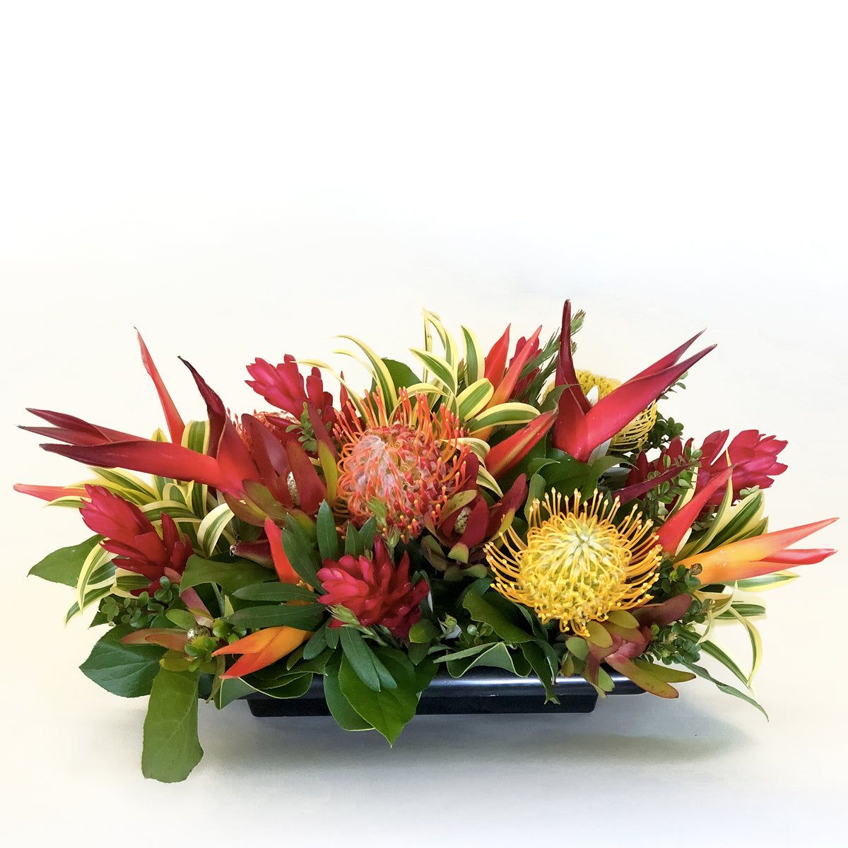 mauifloral's tweet photo. A centerpiece that feels like an island getaway 🌺 The Tropical Paradise Arrangement features fresh pincushion protea, ginger, heliconia, tropic fleur, song of india, and lush greenery in a stunning long, low display. https://t.co/dvqchzgVzU https://t.co/BRjm7LEFGG